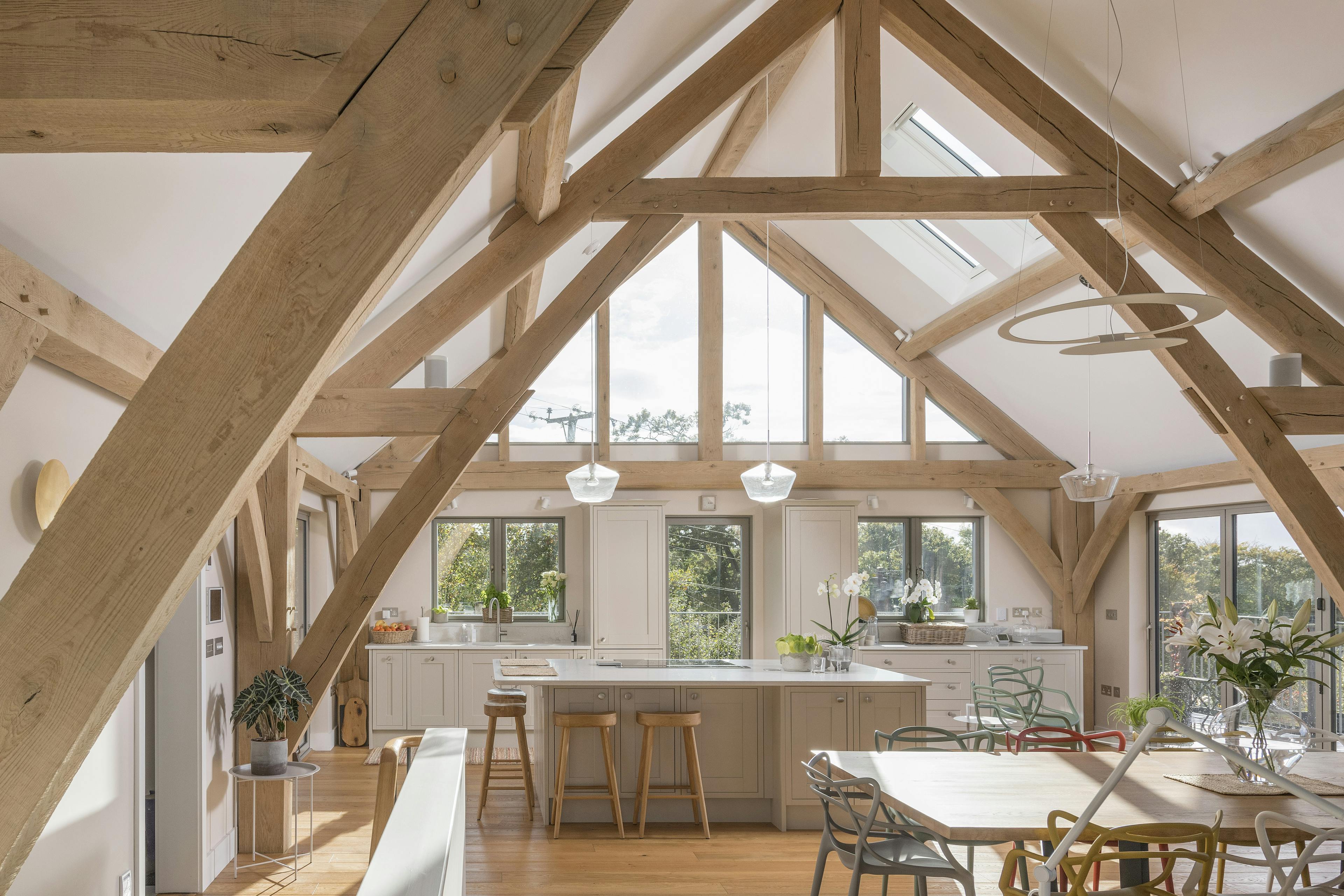 A stairwell leads to a dining area and kitchen in a vaulted oak framed open plan living room 