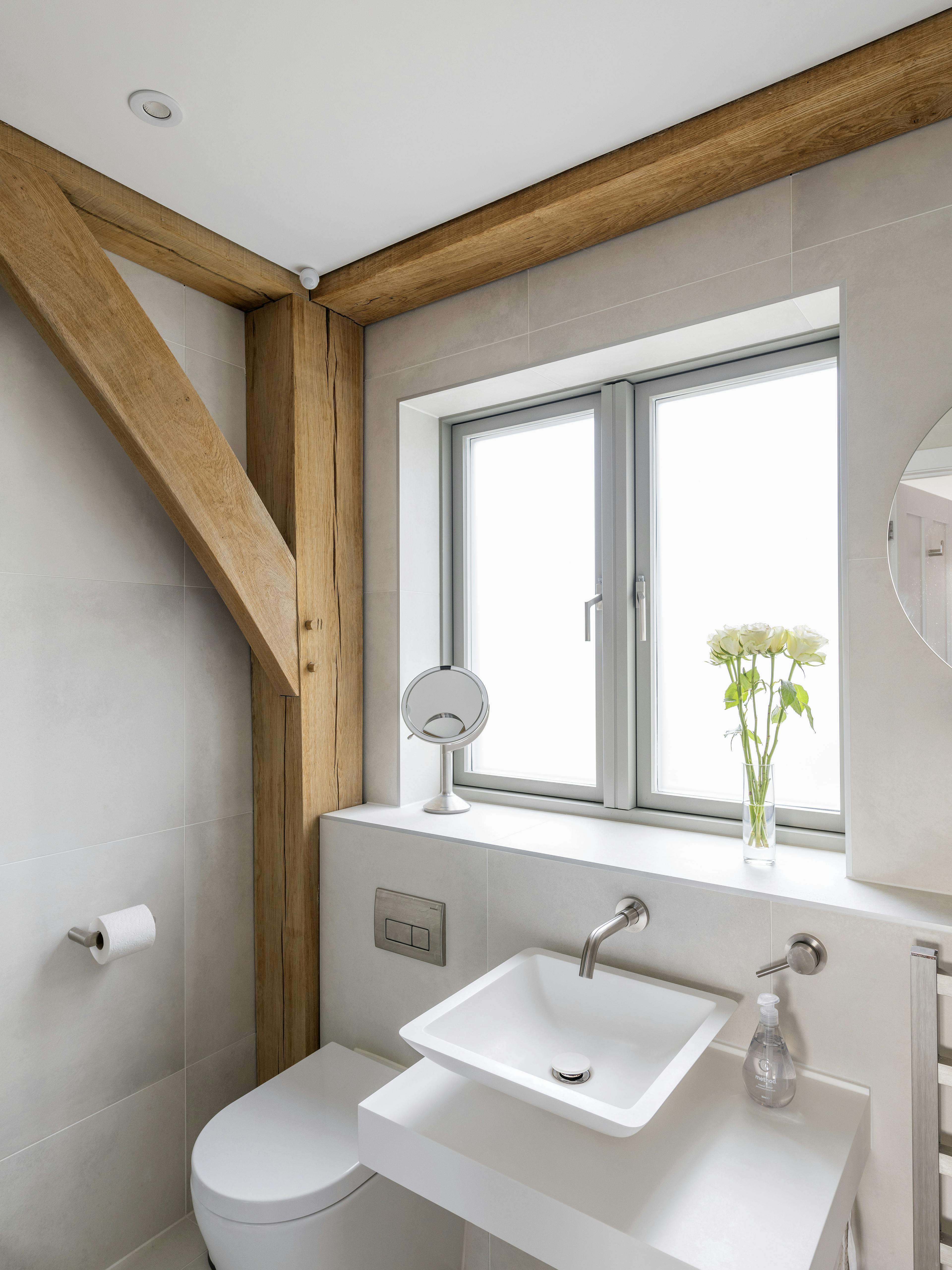 An oak framed bathroom with a white toilet and basin