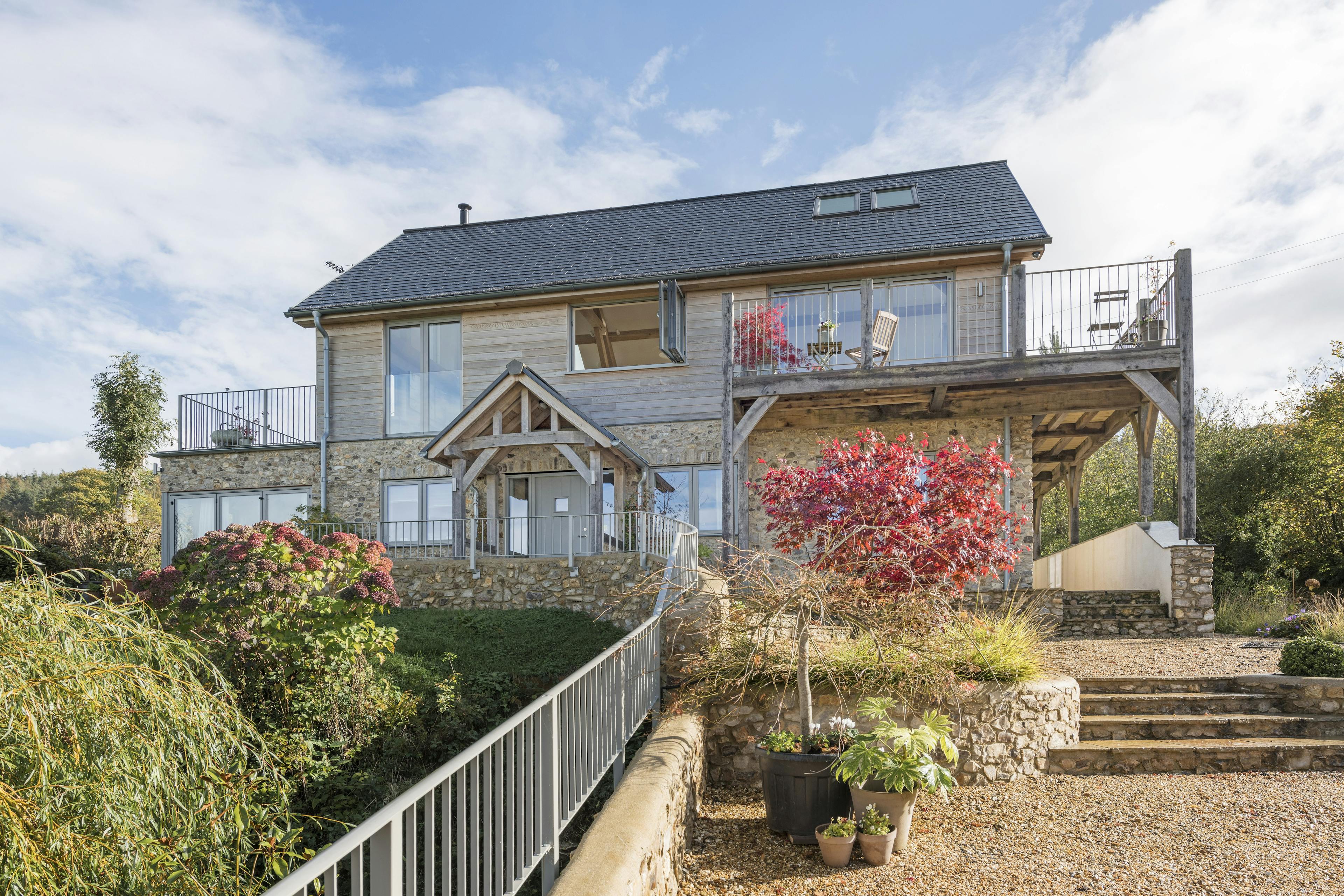 External view of a timber clad oak framed house with oak balconies wrapping round