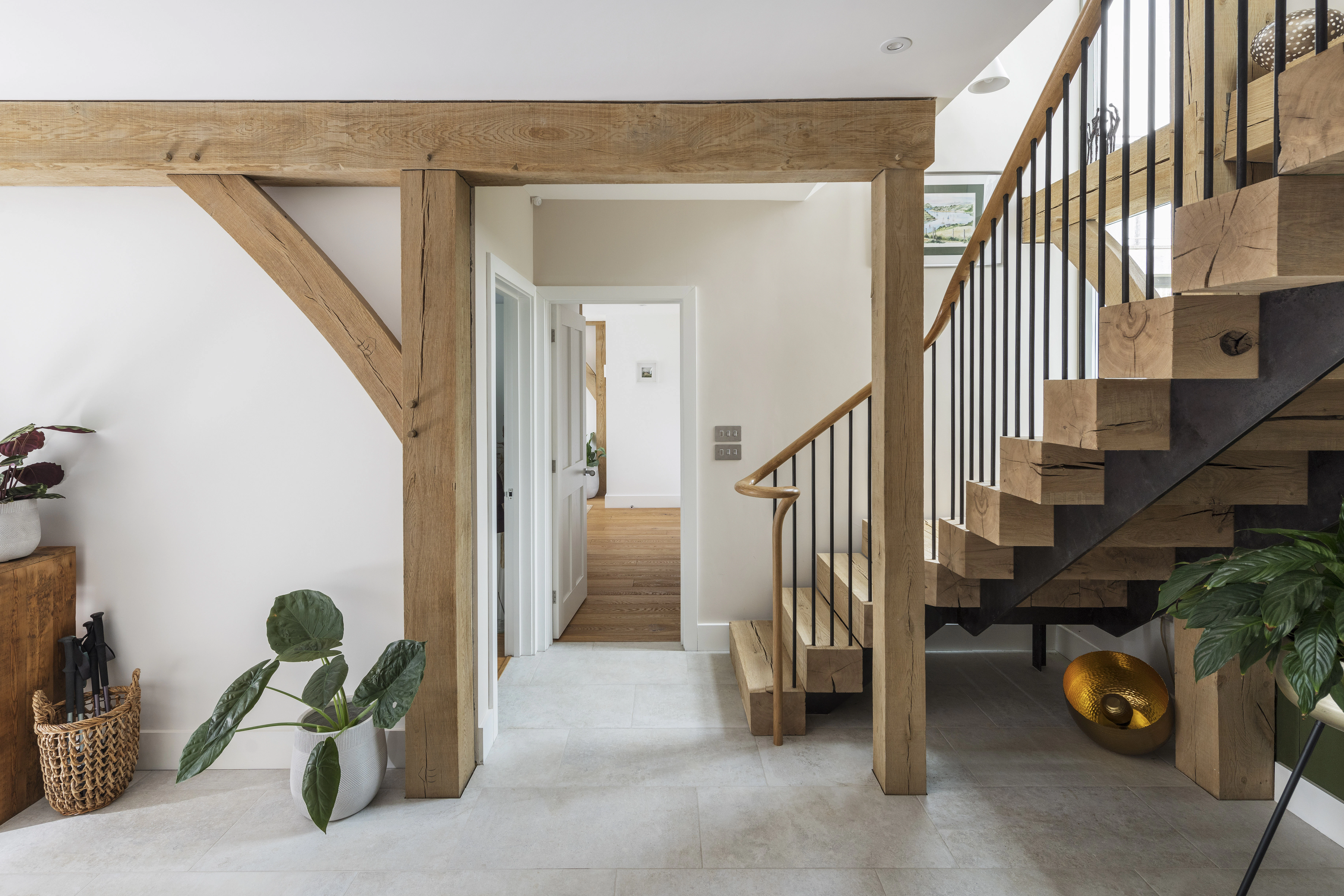 Wooden L shaped stairs nestled into an oak frame lead down to an oak framed hallway