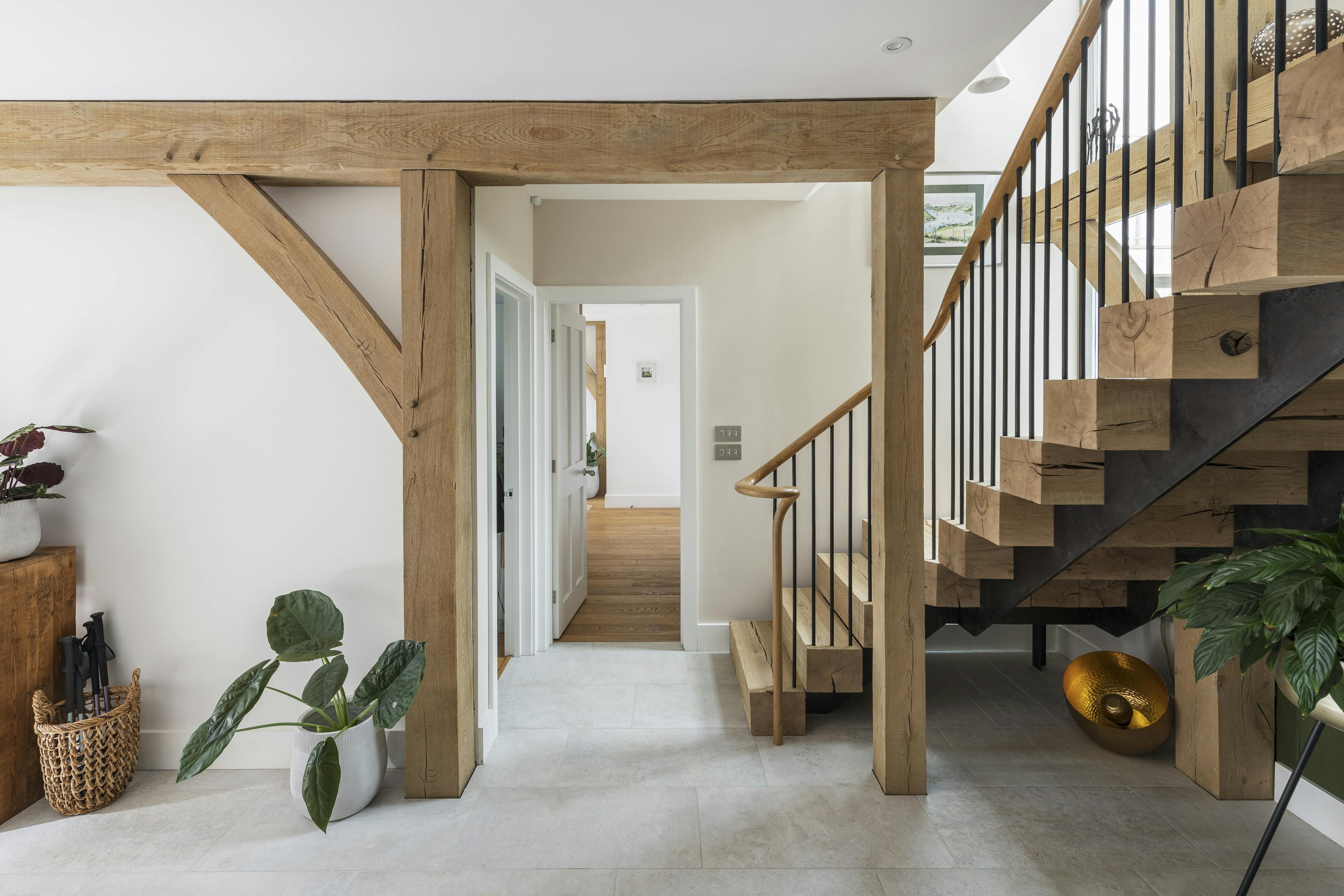 Wooden L shaped stairs nestled into an oak frame lead down to an oak framed hallway