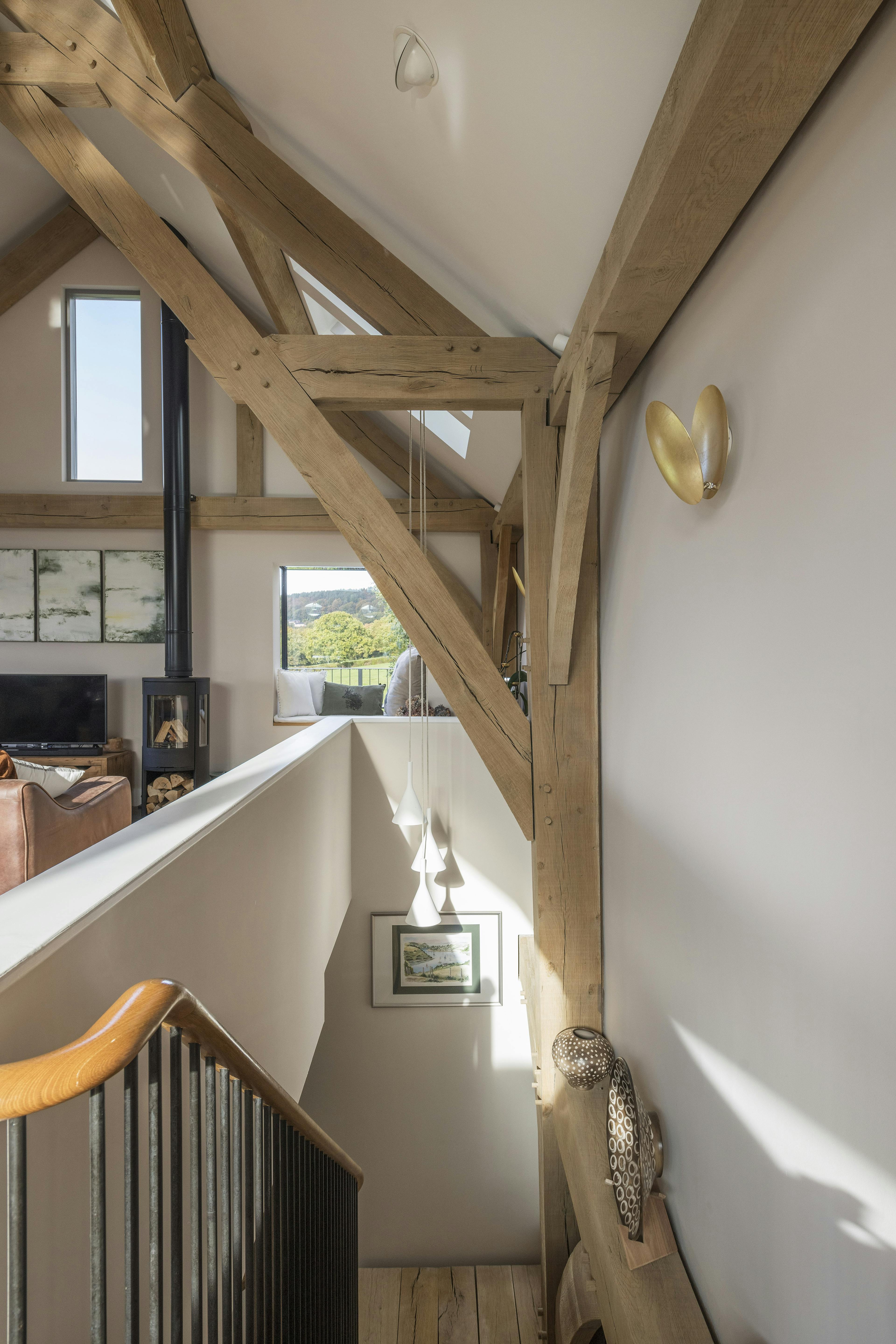 A stairwell under a vaulted oak framed living room