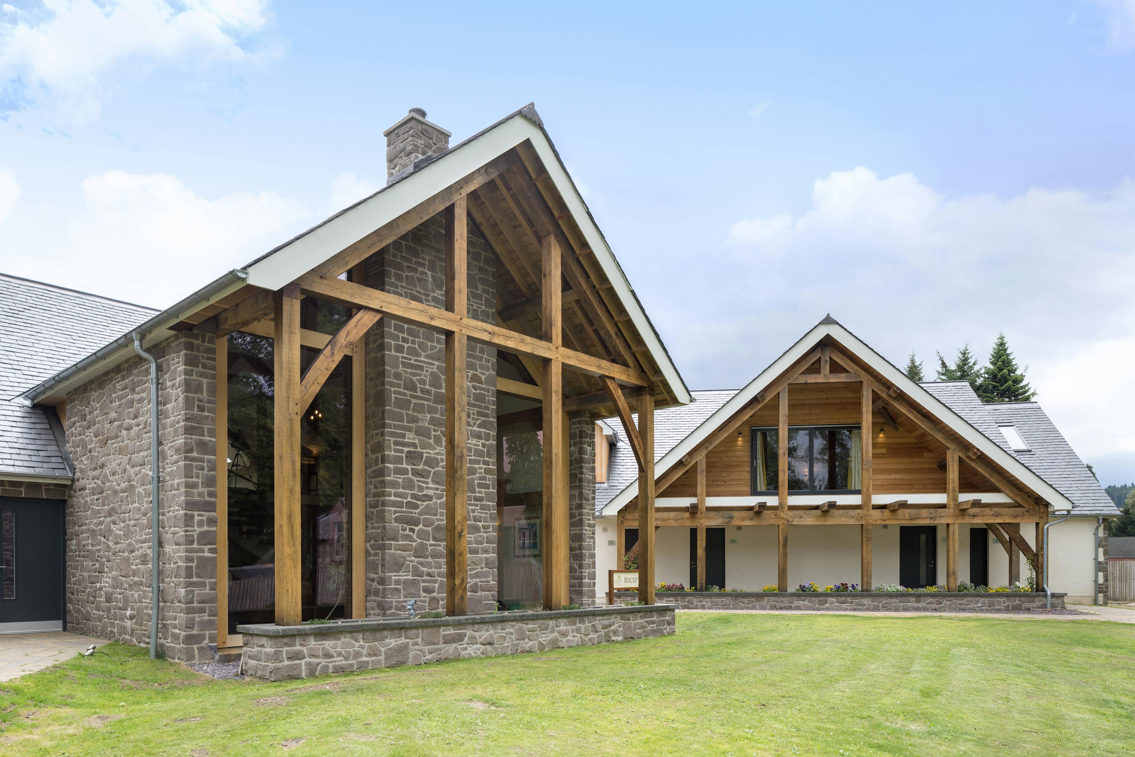 A green lawn in front of two oak framed houses with an oak framed balconies and veranda