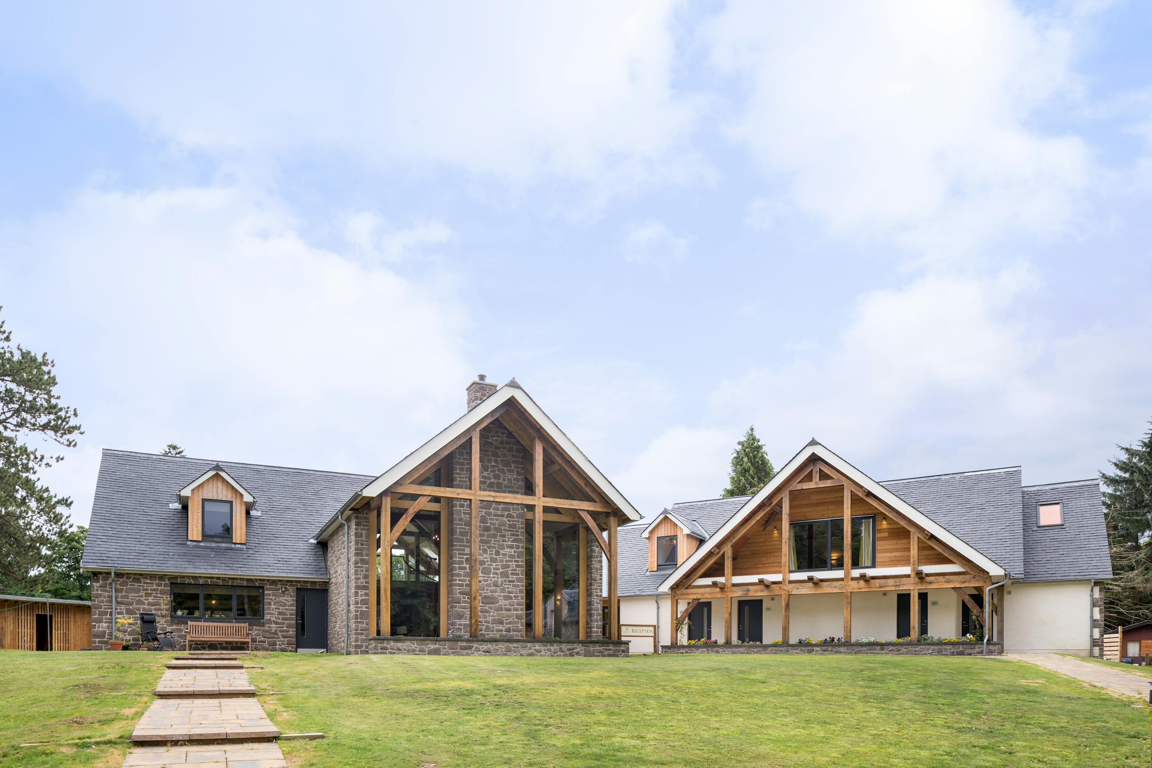 A green lawn in front of two oak framed houses with an oak framed balconies and veranda