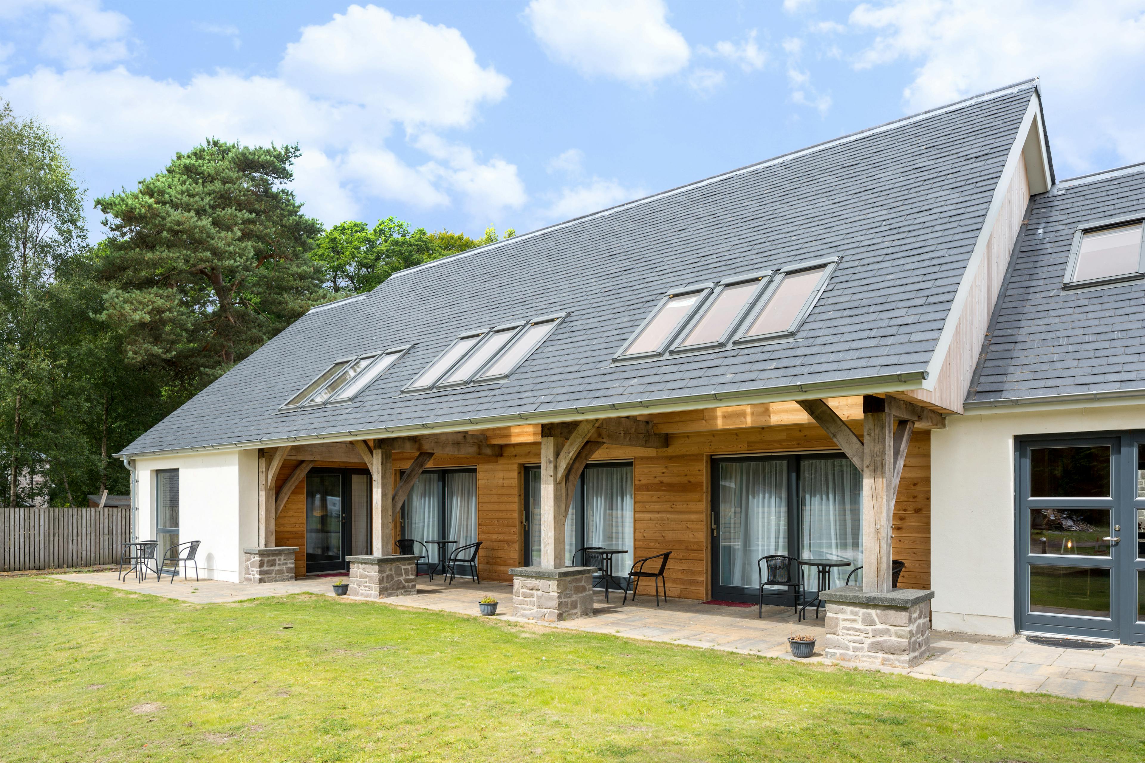 A green lawn in front of an external image of an oak framed house with an oak framed veranda