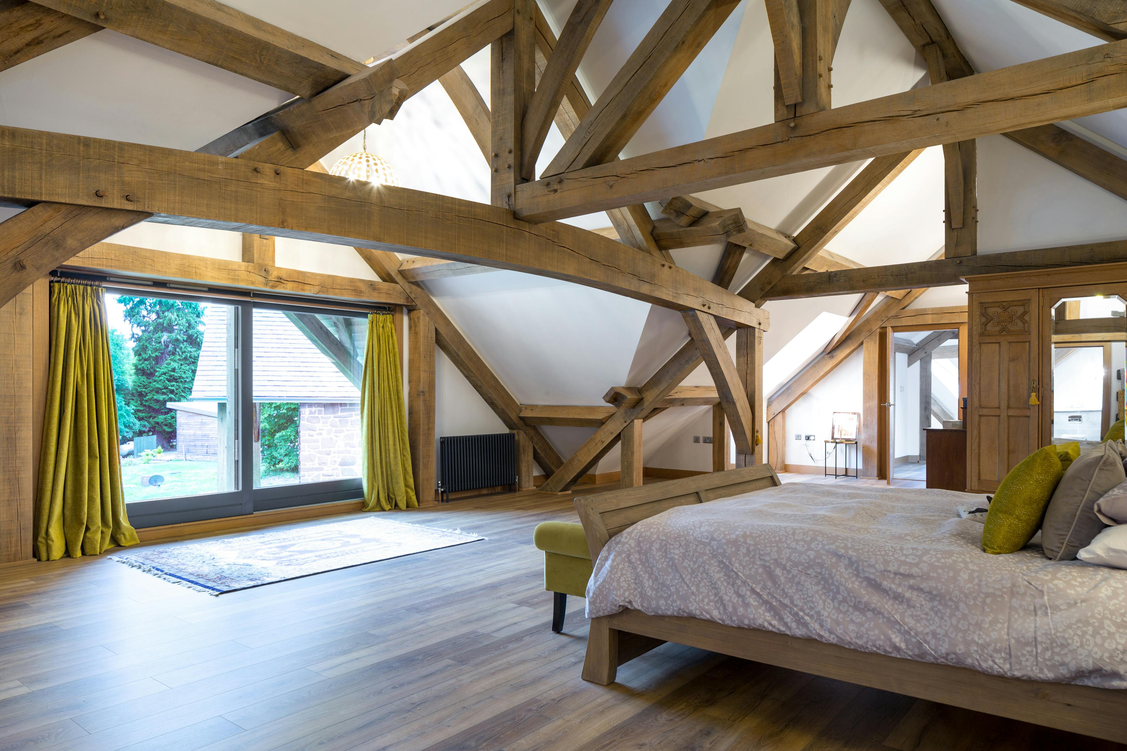 Large oak trusses form a vaulted ceiling in a bedroom