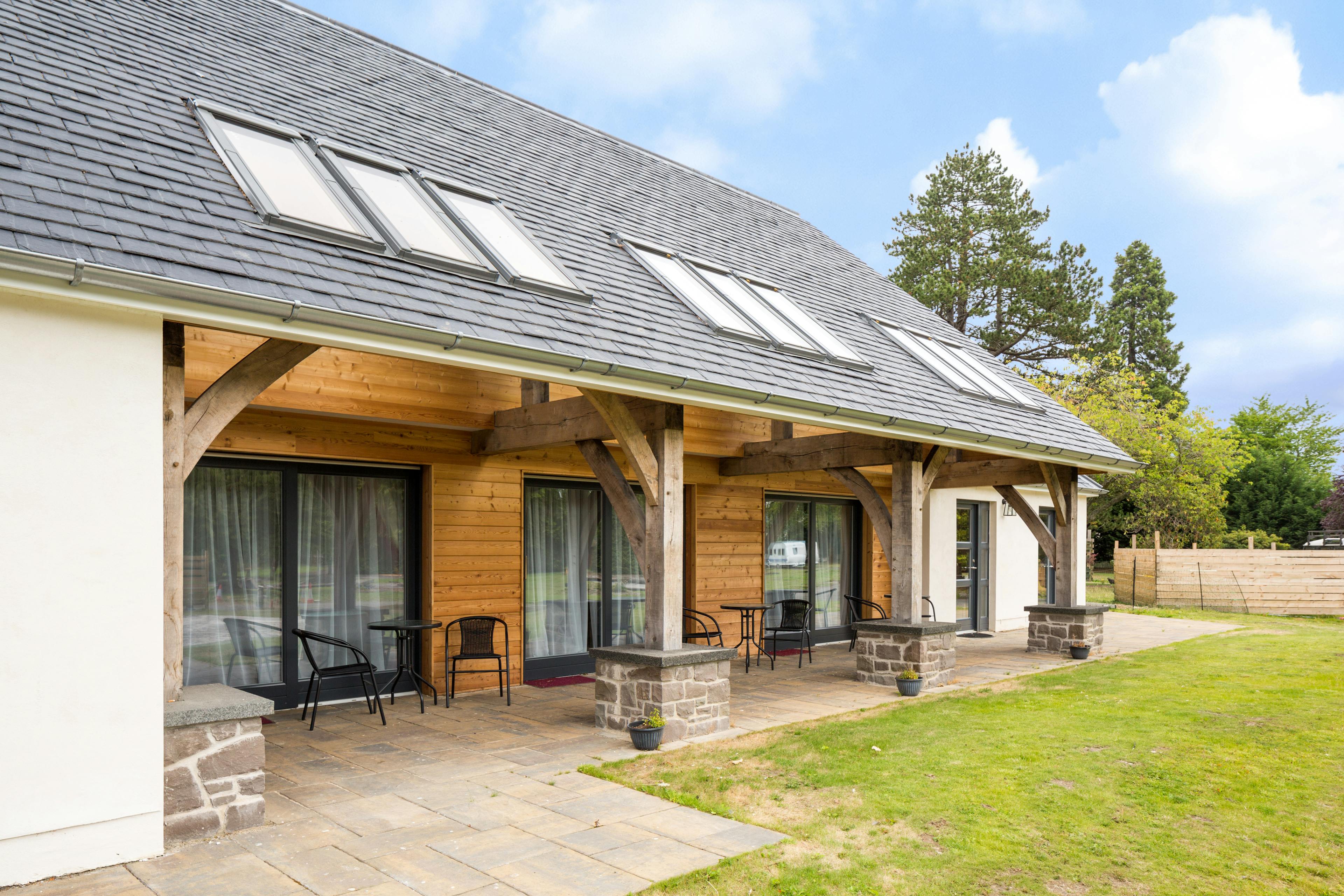 A green lawn in front of an external image of an oak framed house with an oak framed veranda