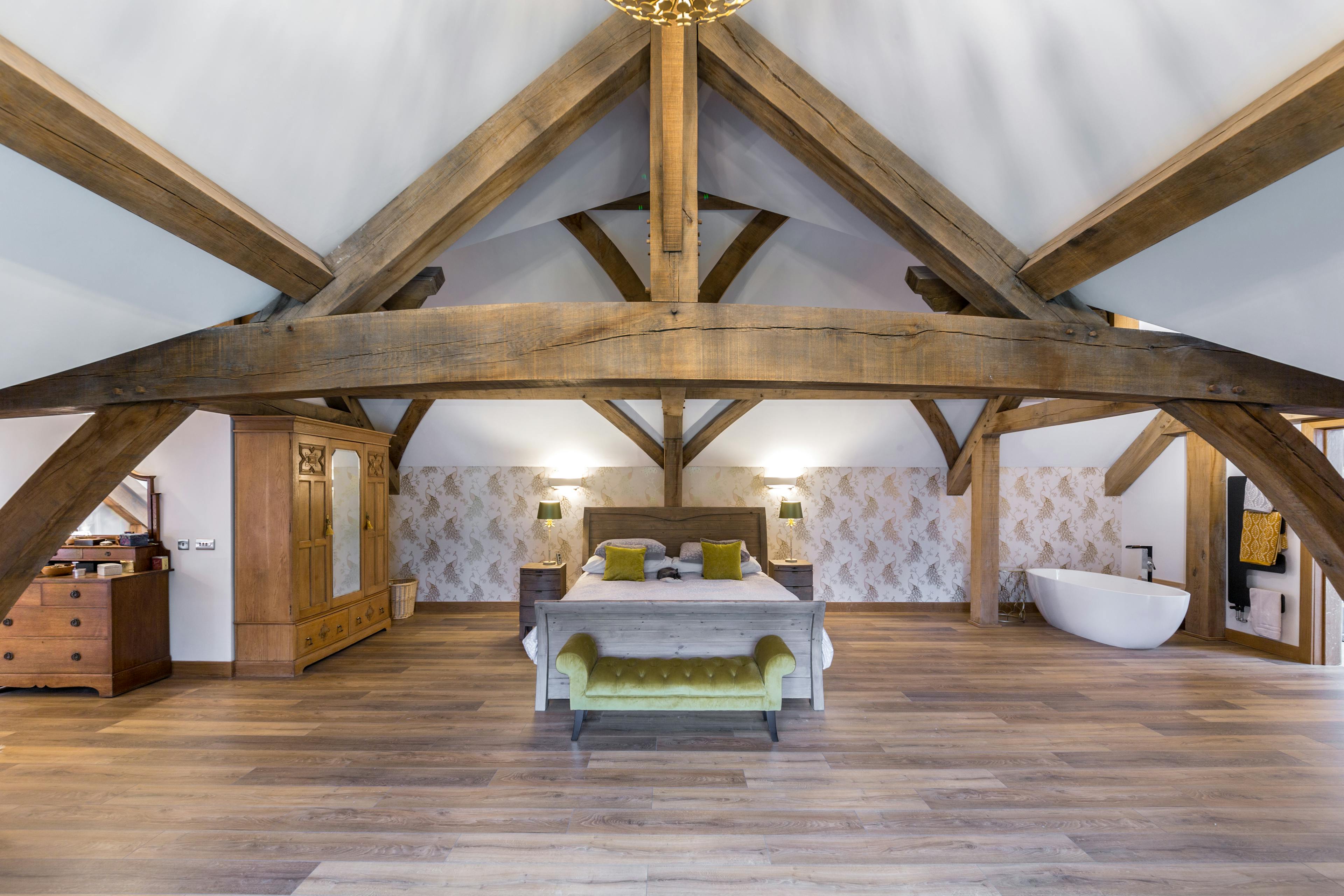 Large oak trusses form a vaulted ceiling in a bedroom