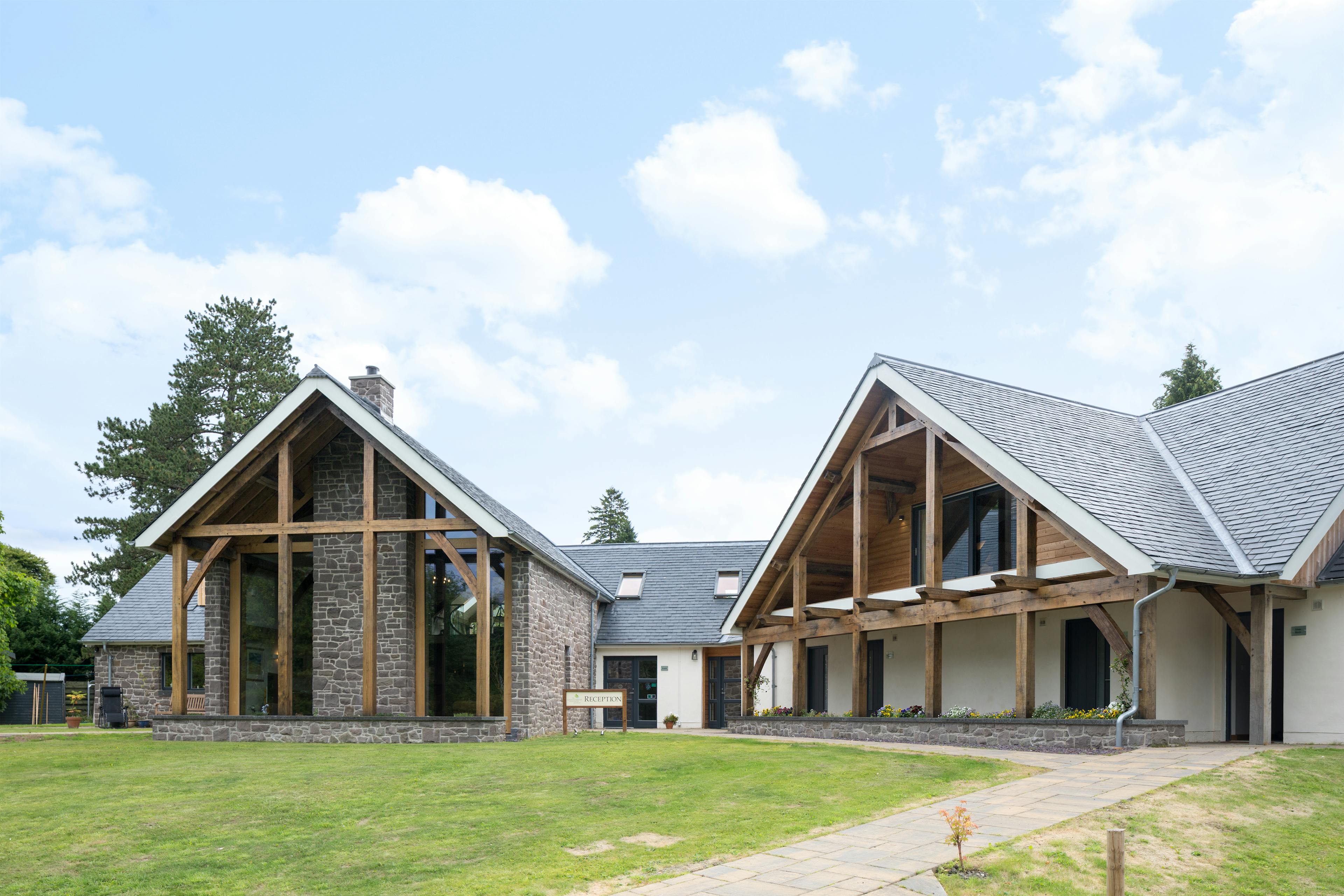 A green lawn in front of two oak framed houses with an oak framed balconies and veranda