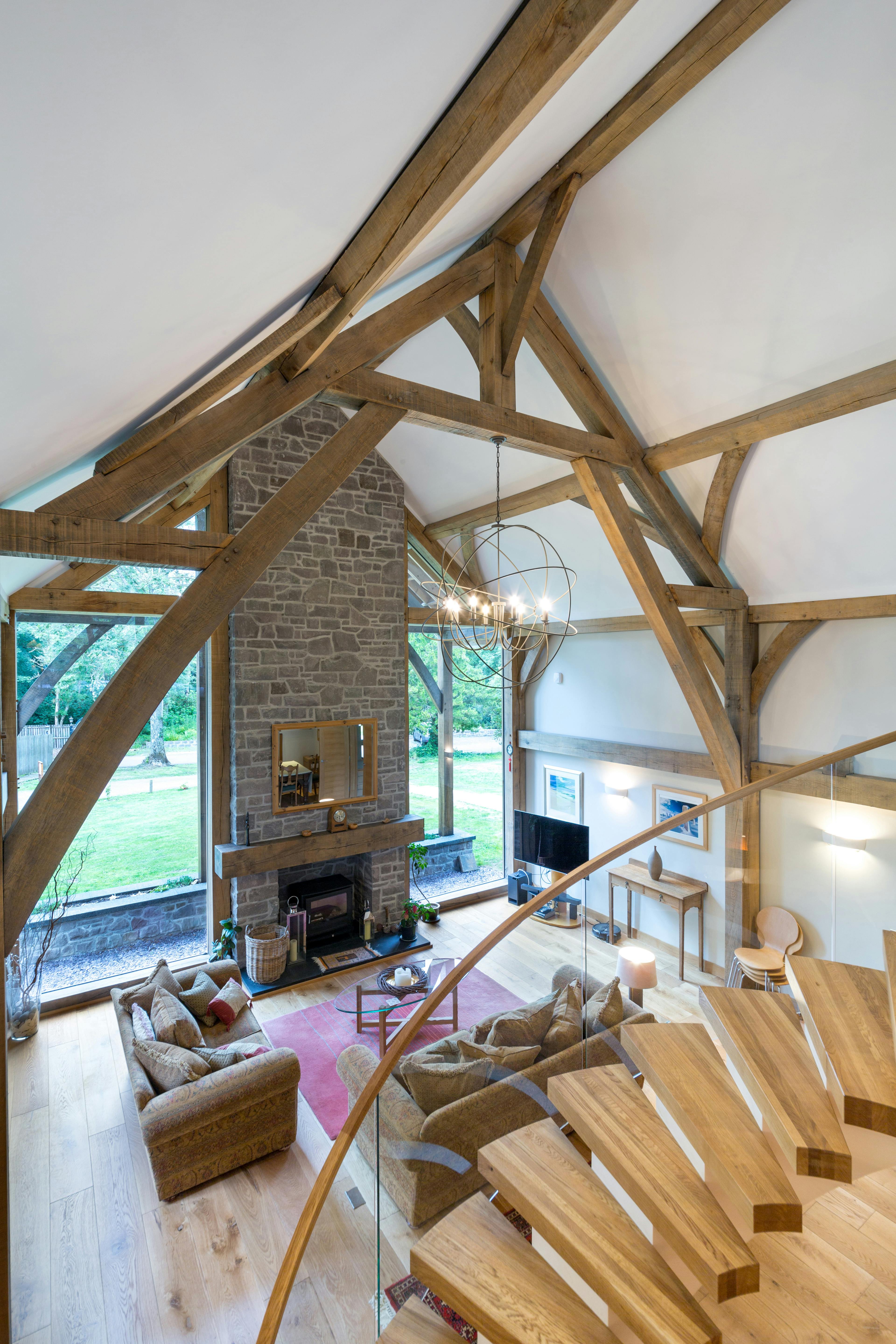 A large living room with a spiral staircase and vaulted oak framed ceiling