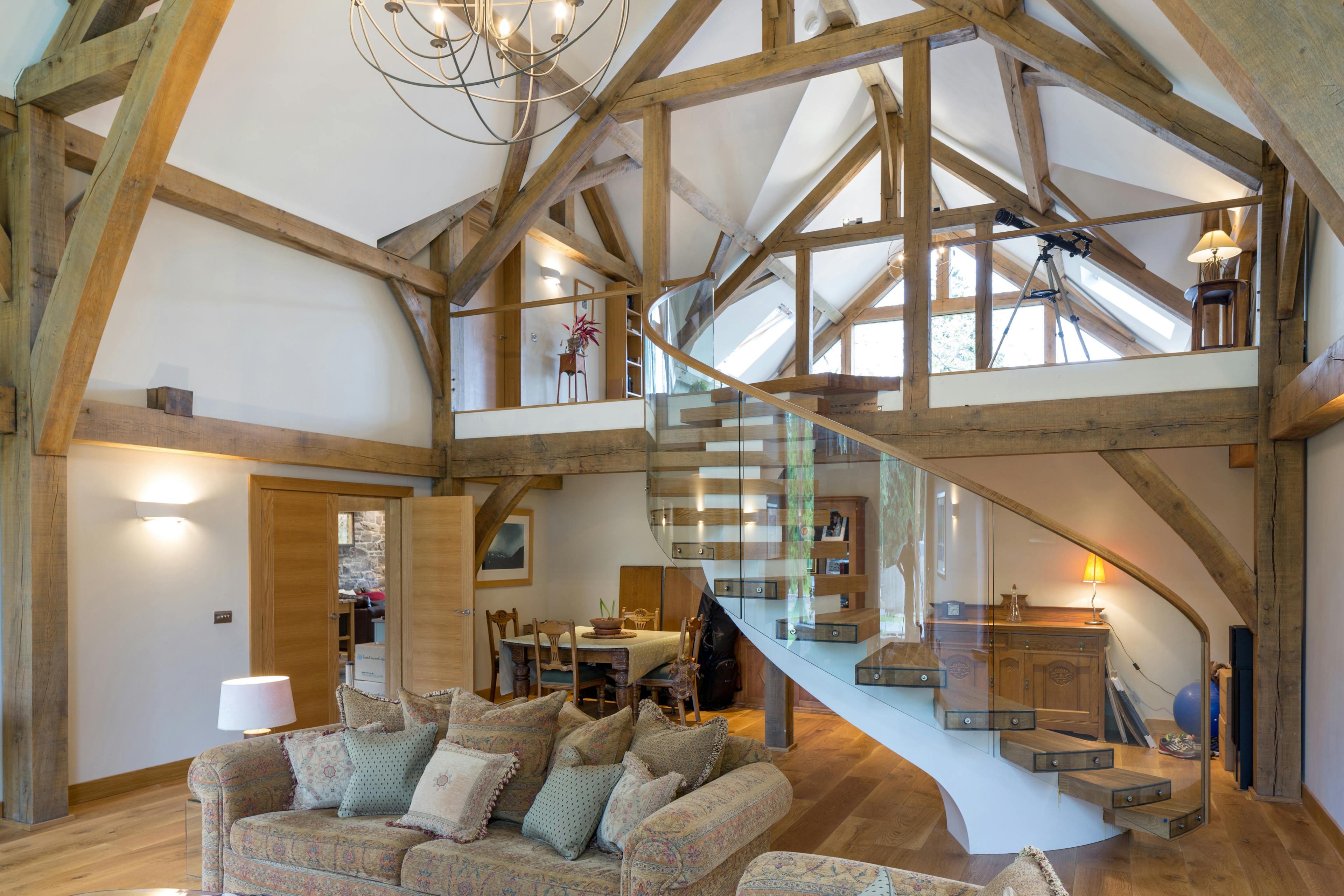 A large living room with a spiral staircase and vaulted oak framed ceiling