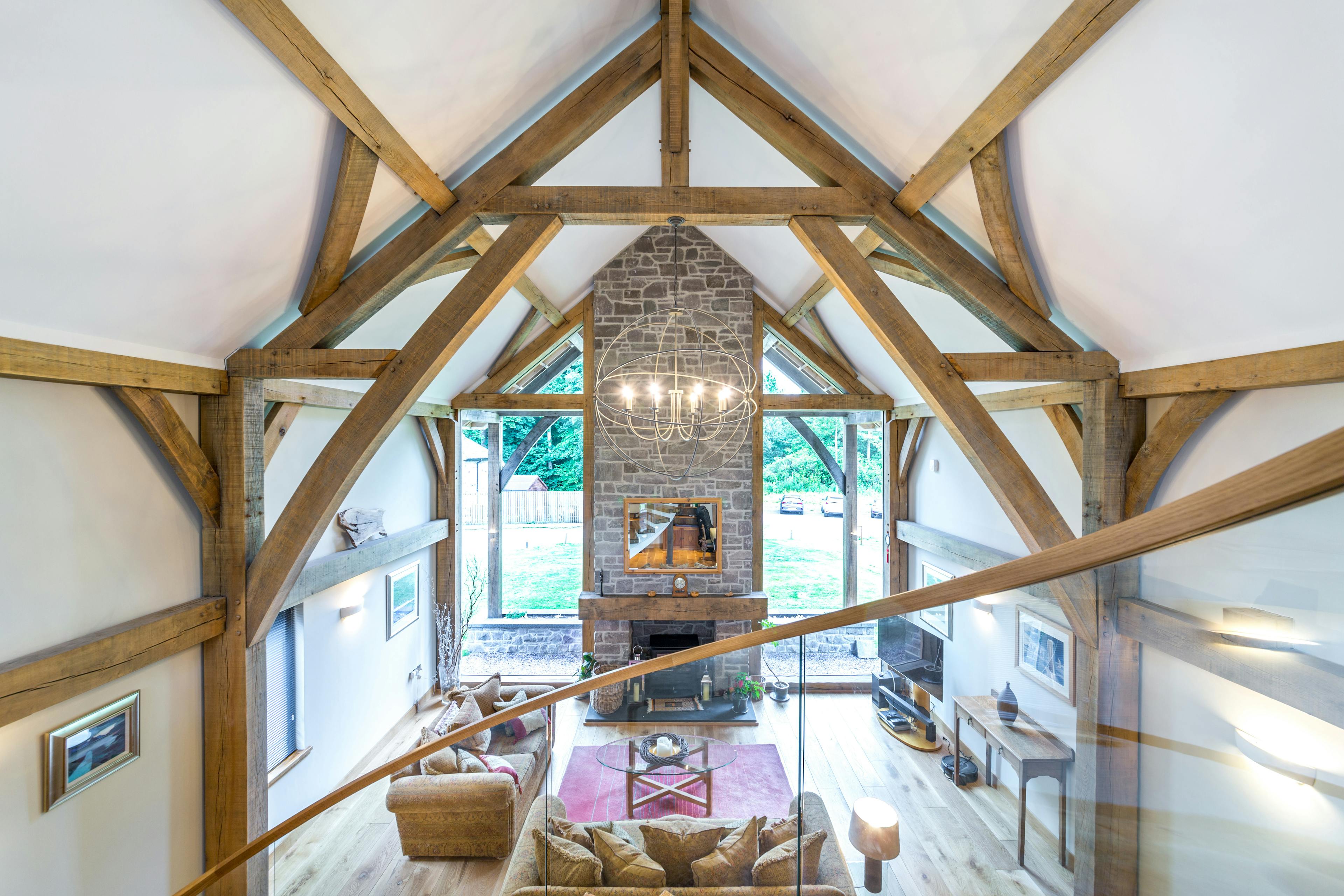 A large living room with sofas and a fireplace and a vaulted oak framed ceiling