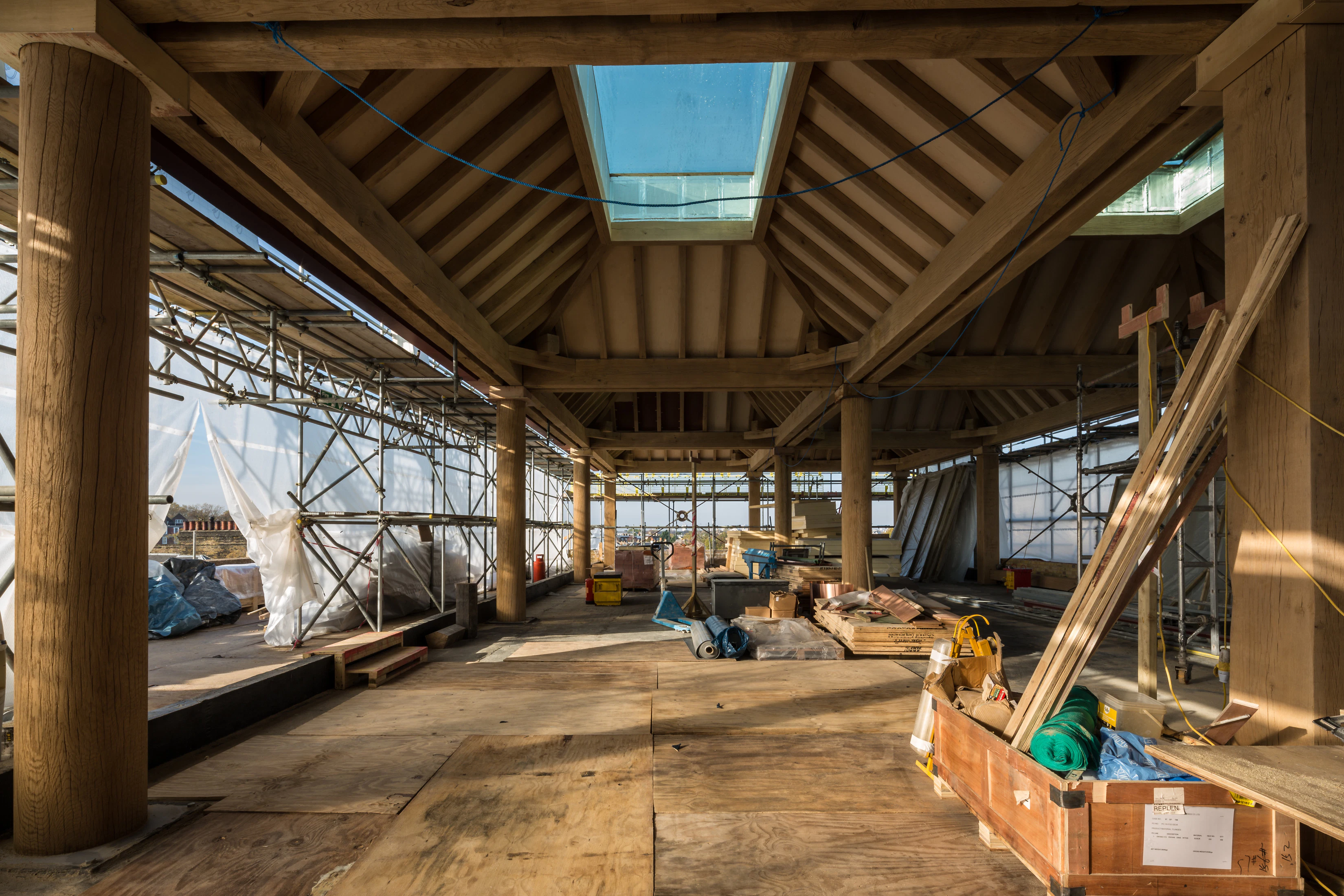 Turned oak columns hold up oak lanterns on a construction site for a rooftop bar in a city