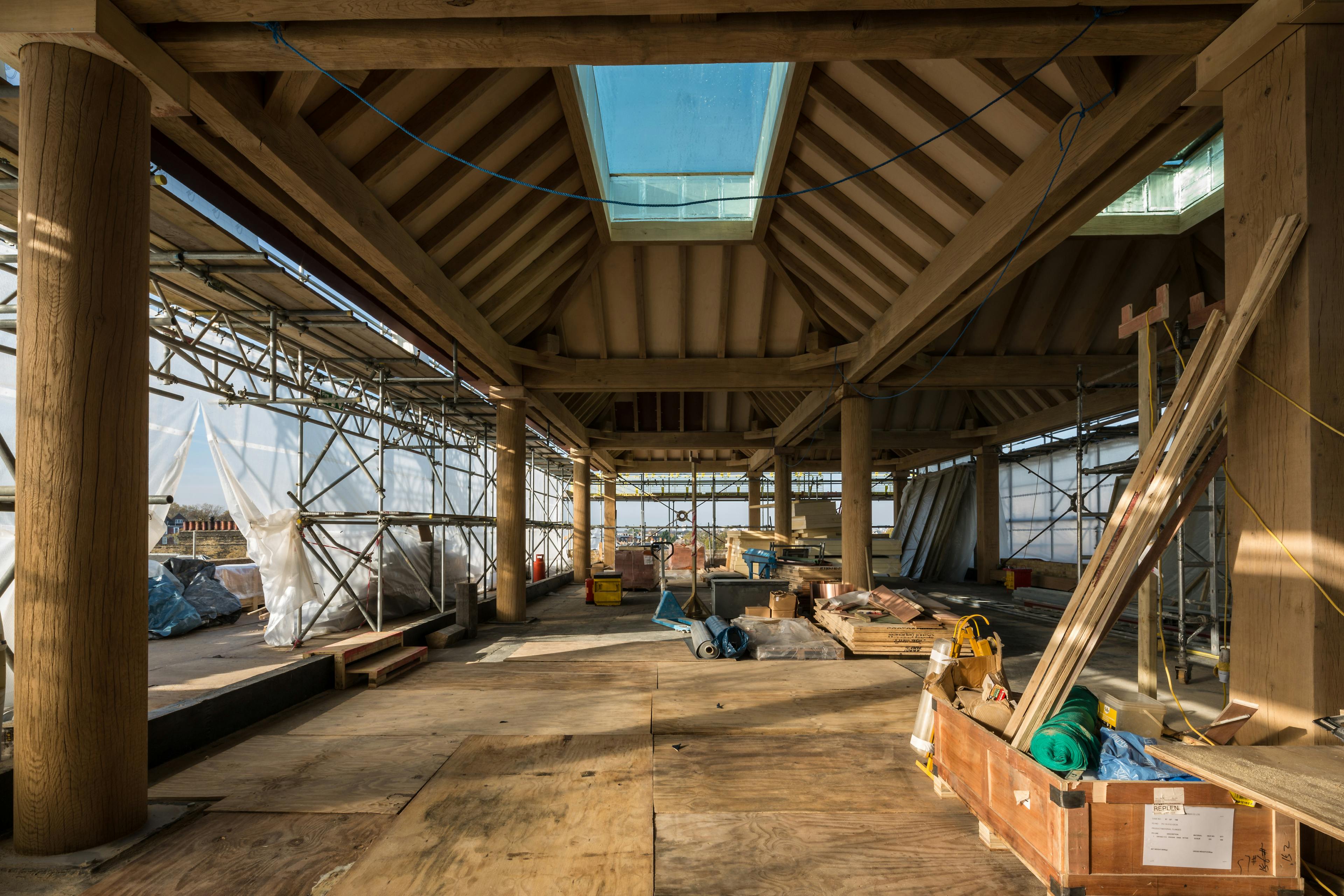 Turned oak columns hold up oak lanterns on a construction site for a rooftop bar in a city