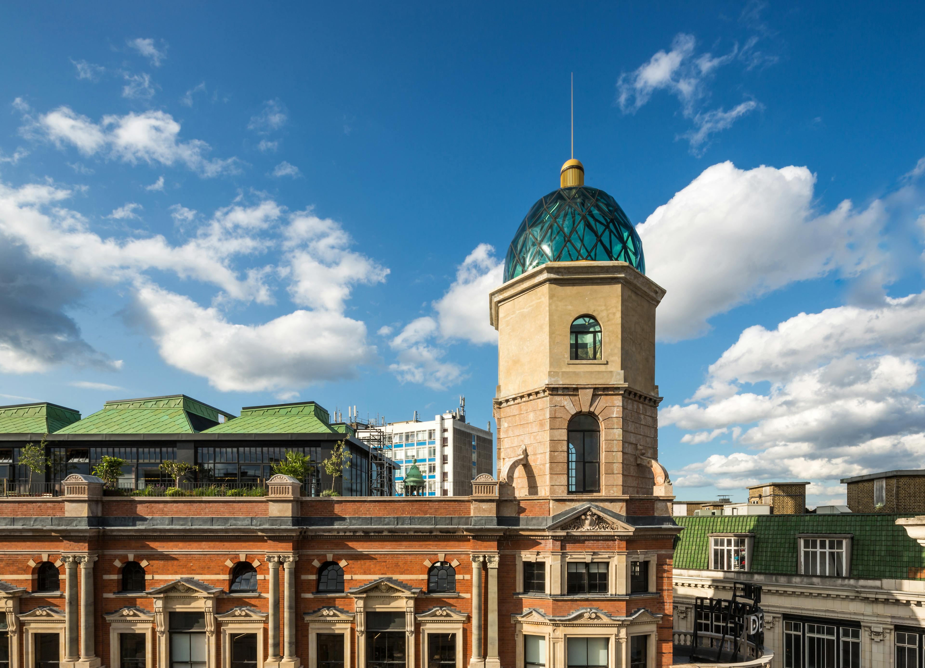 A rooftop bar on a large building in an urban area, with a blue sky and white clouds behind