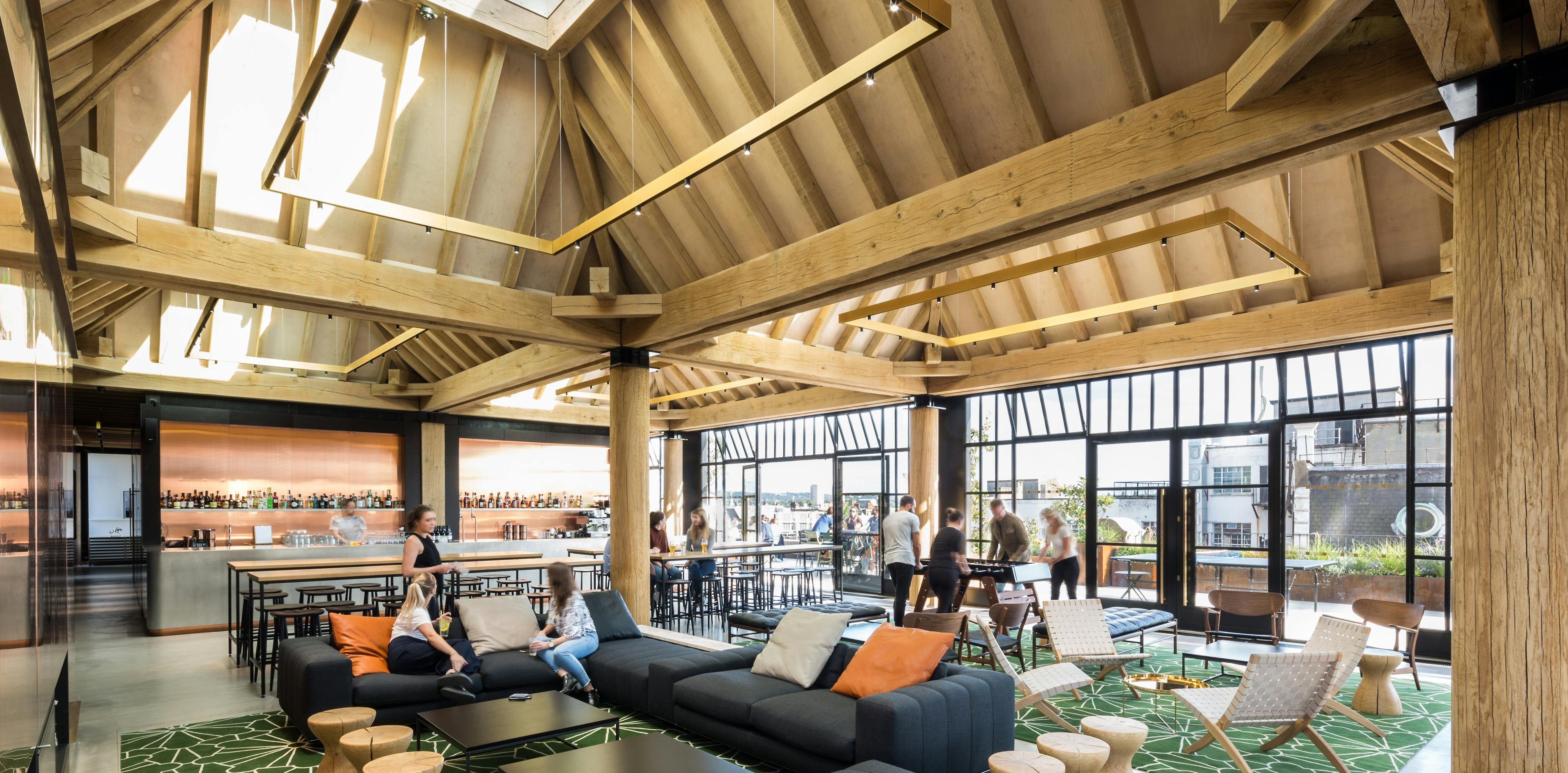 Oak frame lanterns link to create a rooftop bar with customers sat at tables and sofas