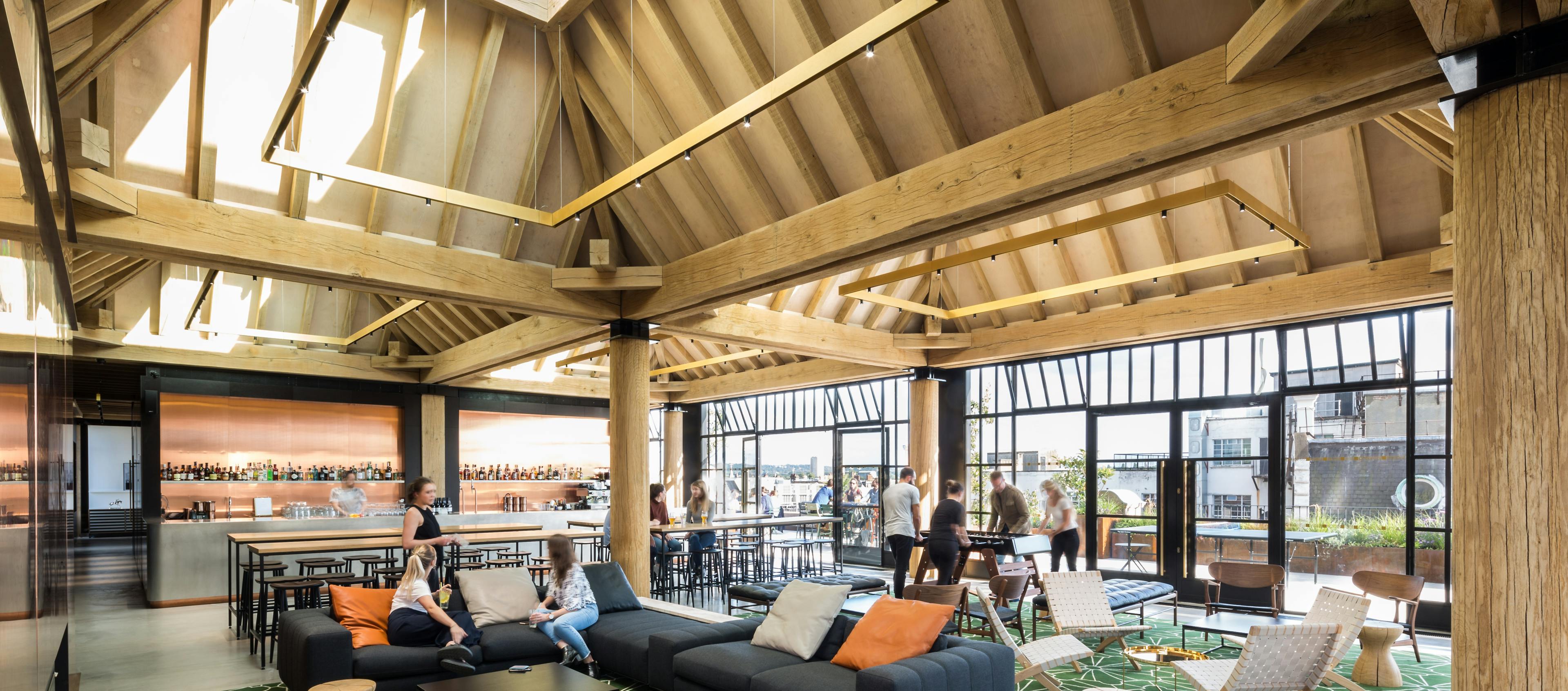 Oak frame lanterns link to create a rooftop bar with customers sat at tables and sofas