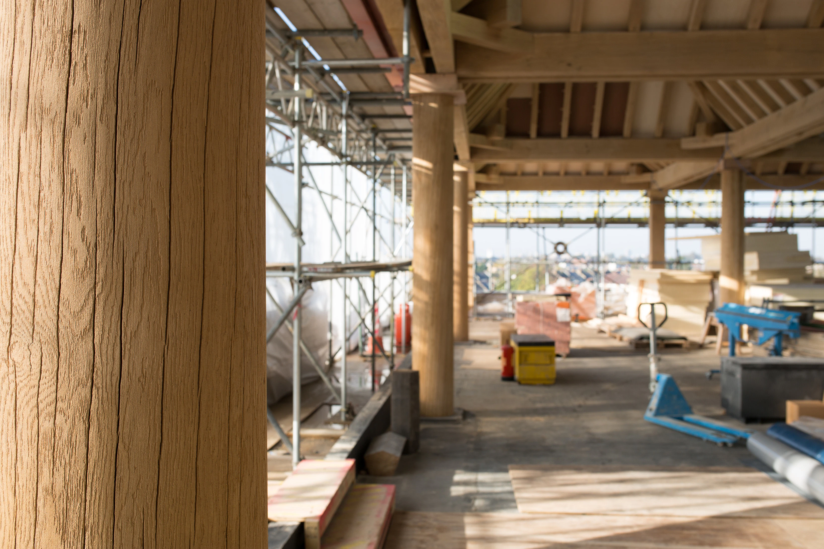 Turned oak columns hold up oak lanterns on a construction site for a rooftop bar in a city