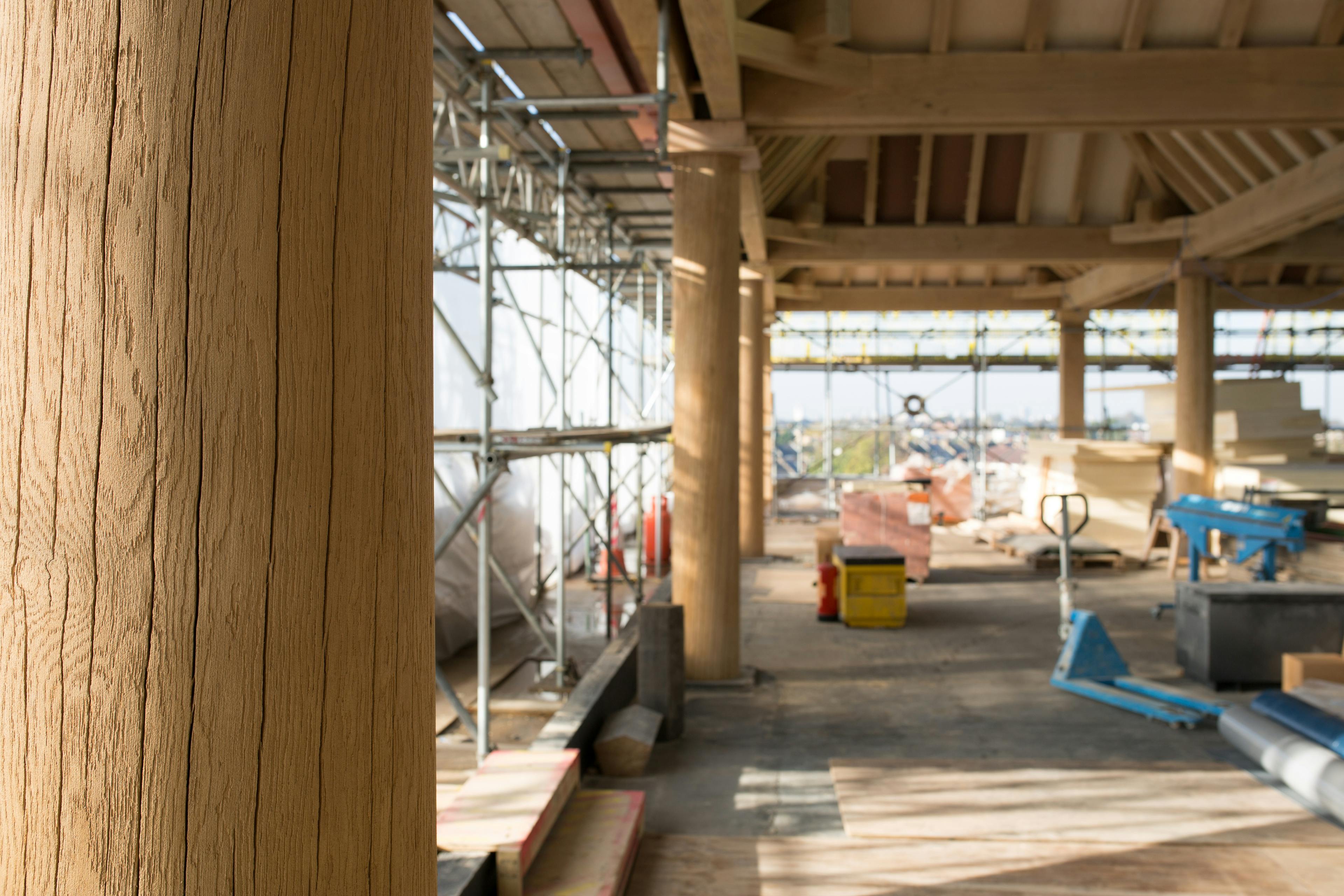 Turned oak columns hold up oak lanterns on a construction site for a rooftop bar in a city