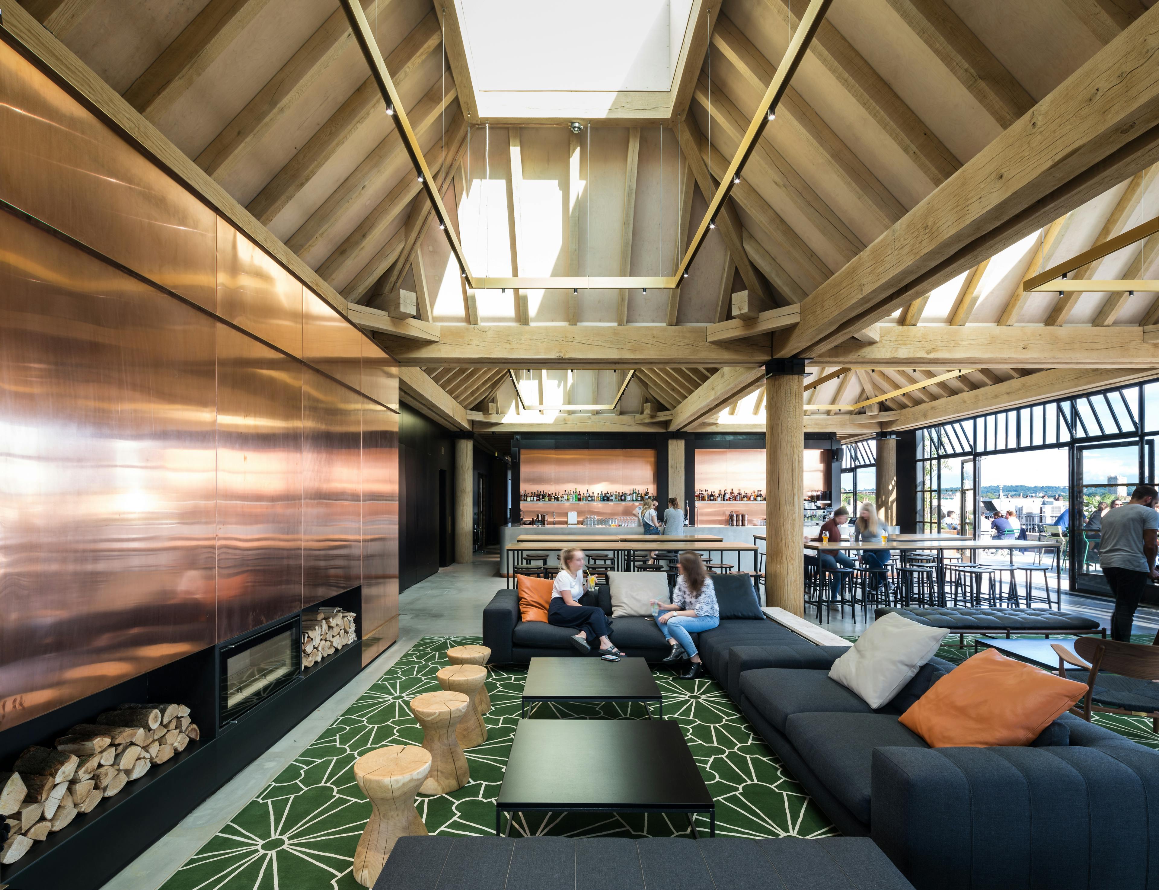 Oak frame lanterns link to create a rooftop bar with customers sat at tables and sofas