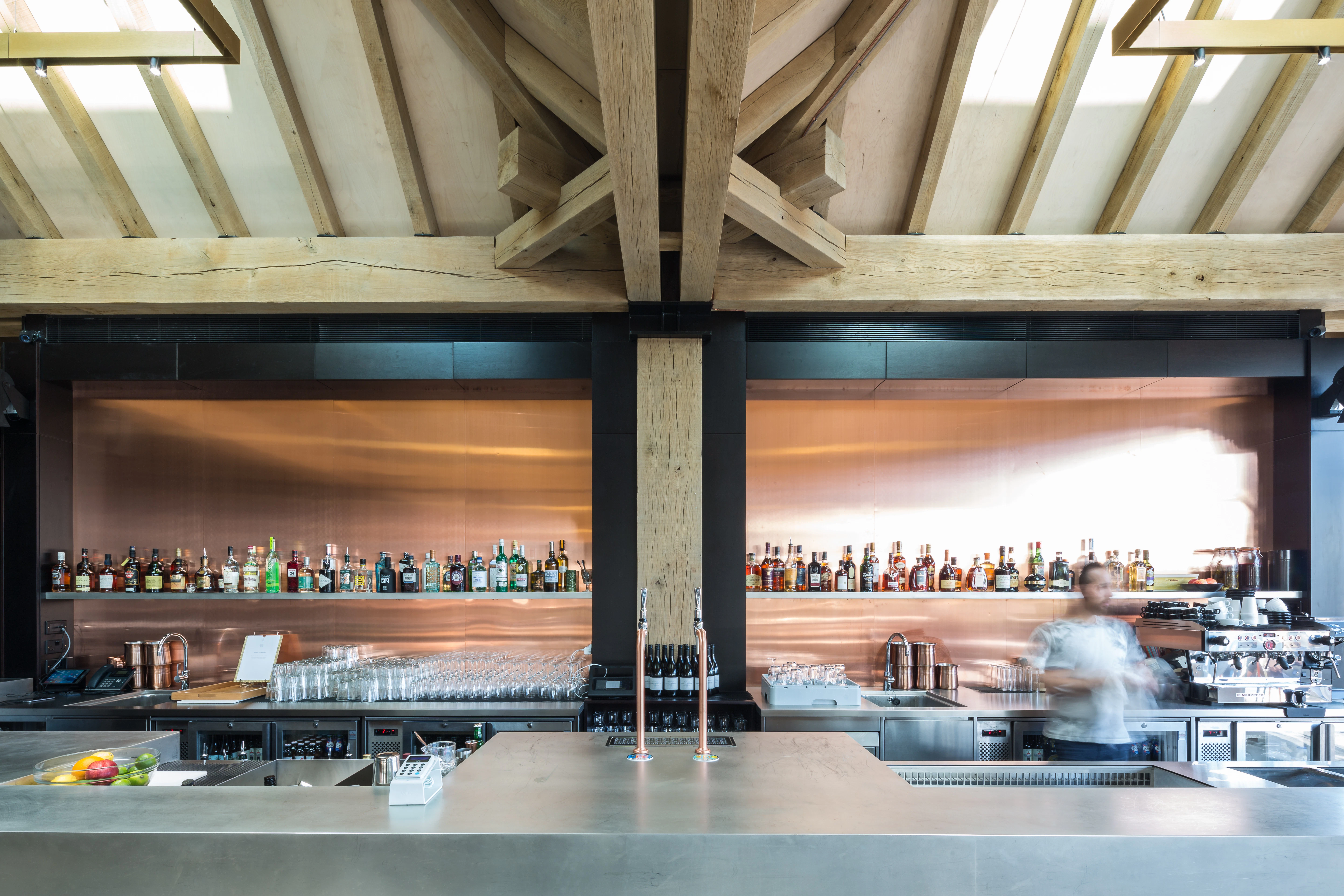 A blurred photo shows a worker behind an oak frame bar