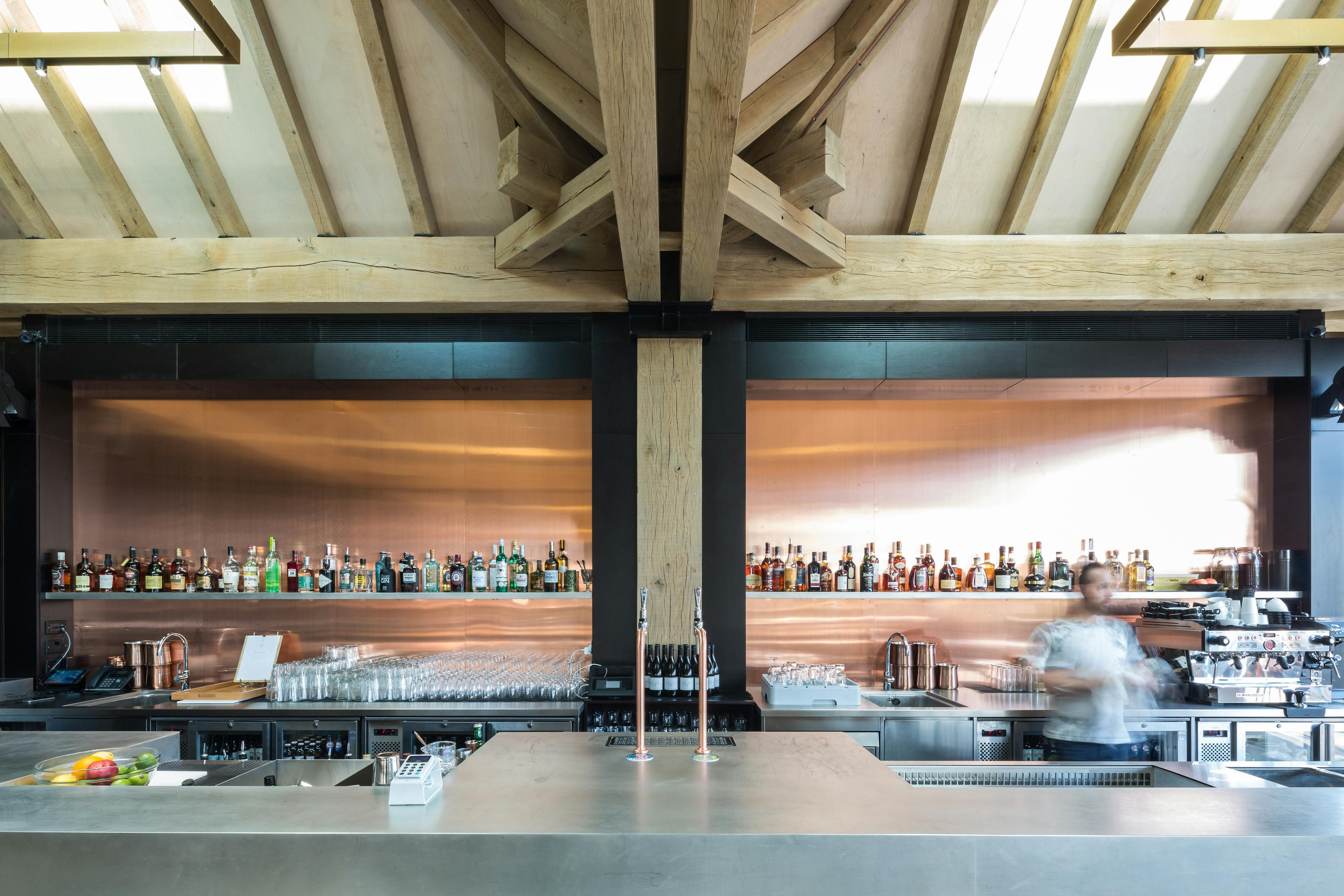 A blurred photo shows a worker behind an oak frame bar