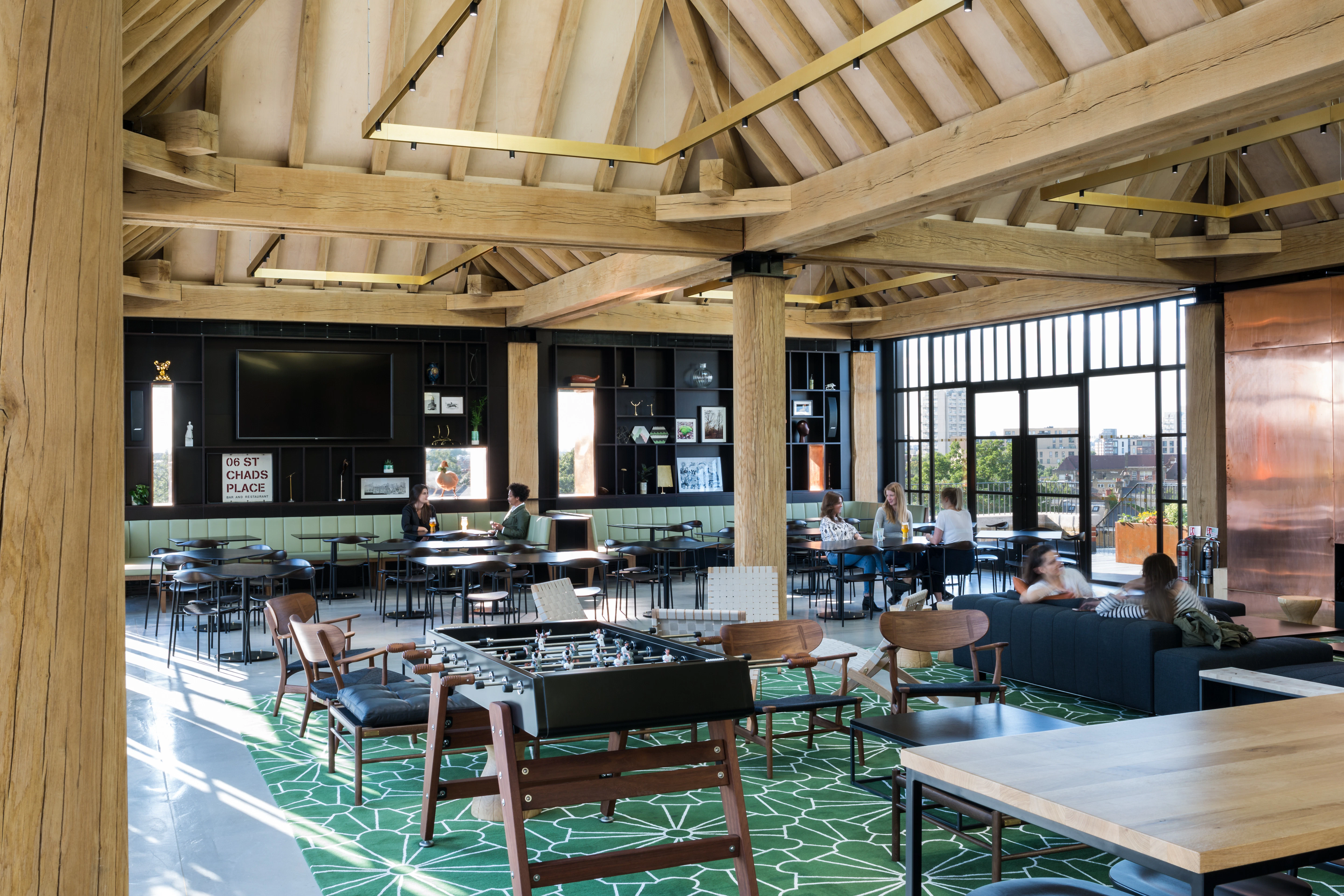 Oak frame lanterns link to create a rooftop bar with customers sat at tables and sofas