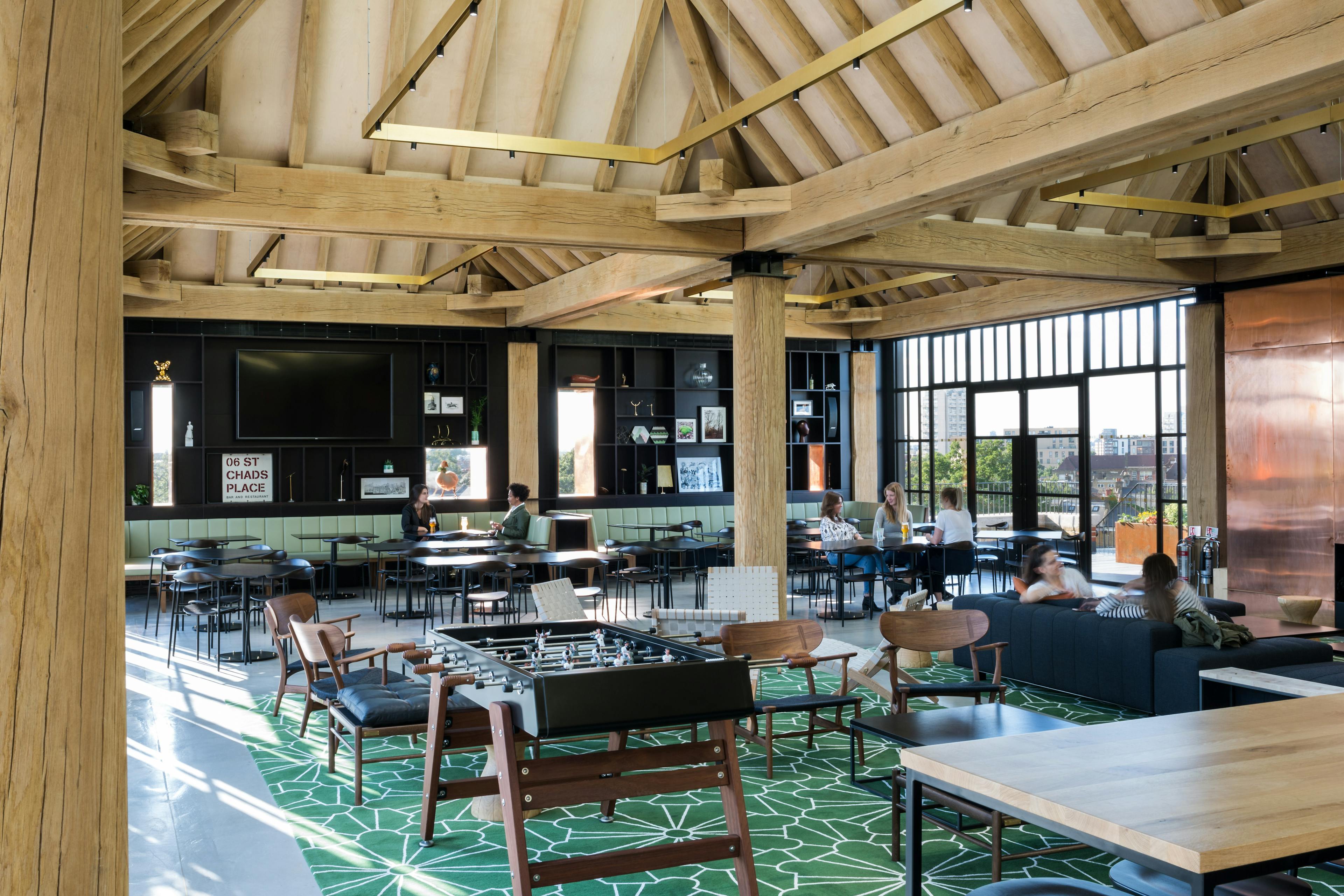 Oak frame lanterns link to create a rooftop bar with customers sat at tables and sofas