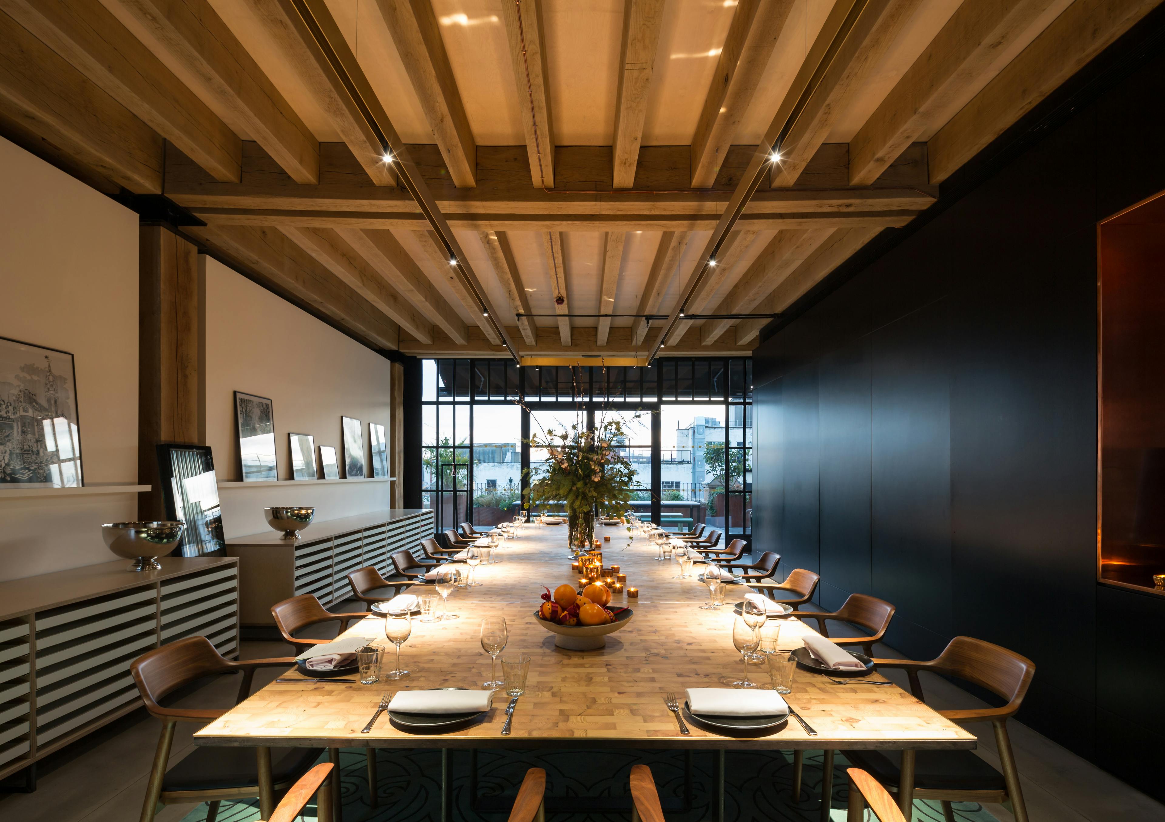 A large table is laid out in an oak frame dining area of a rooftop bar 