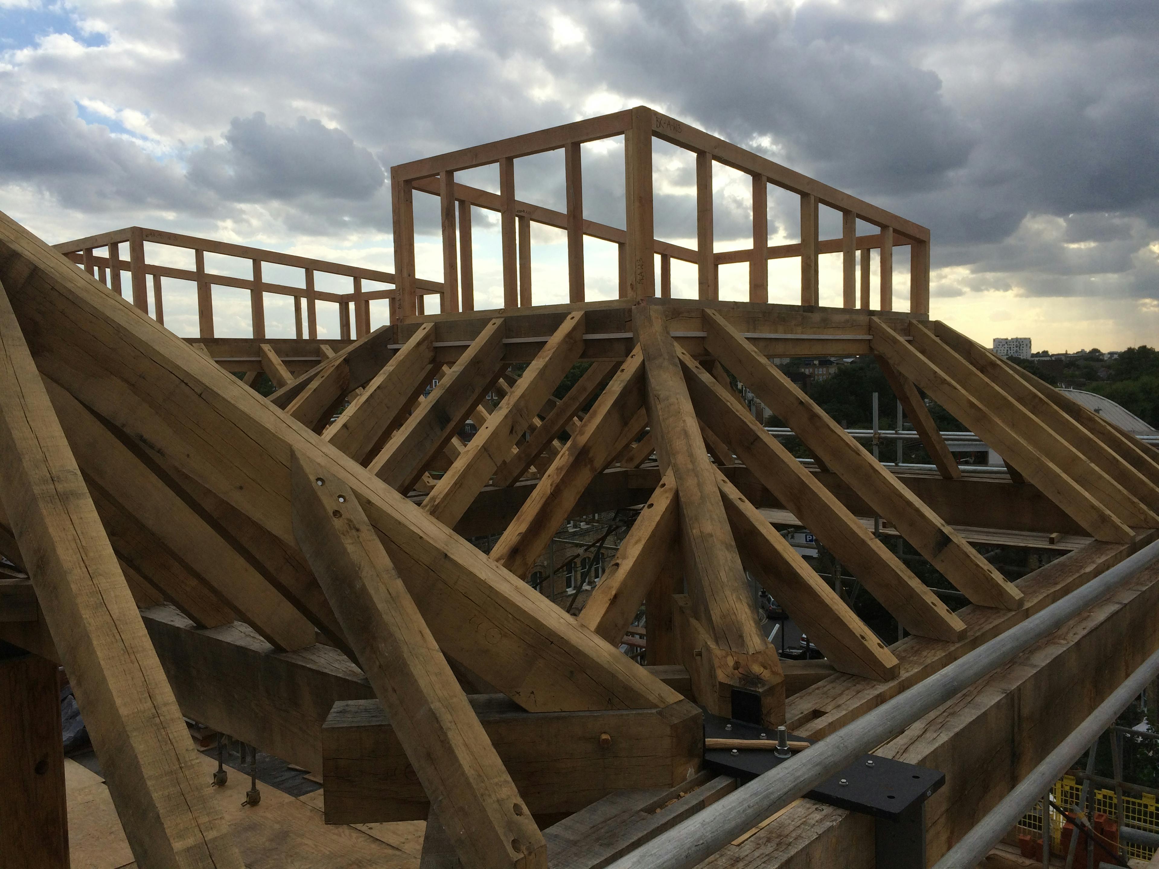 Oak lantern frames being constructed on a rooftop with cloudy skies behind