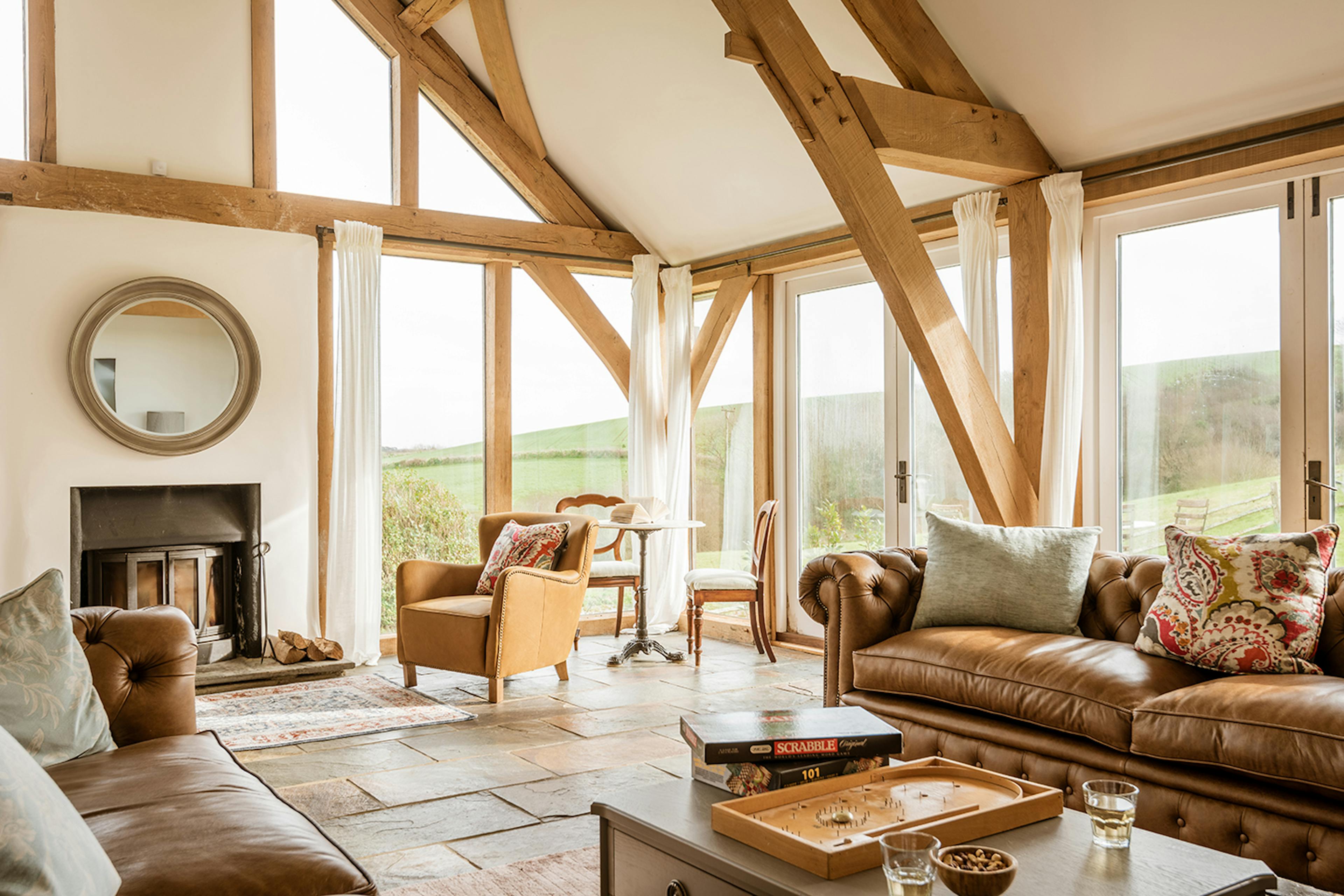 An oak framed extension with sitting area with leather sofas and a log burner