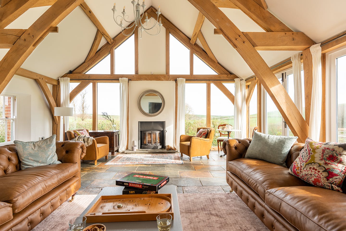 An oak framed extension with sitting area with leather sofas and a log burner