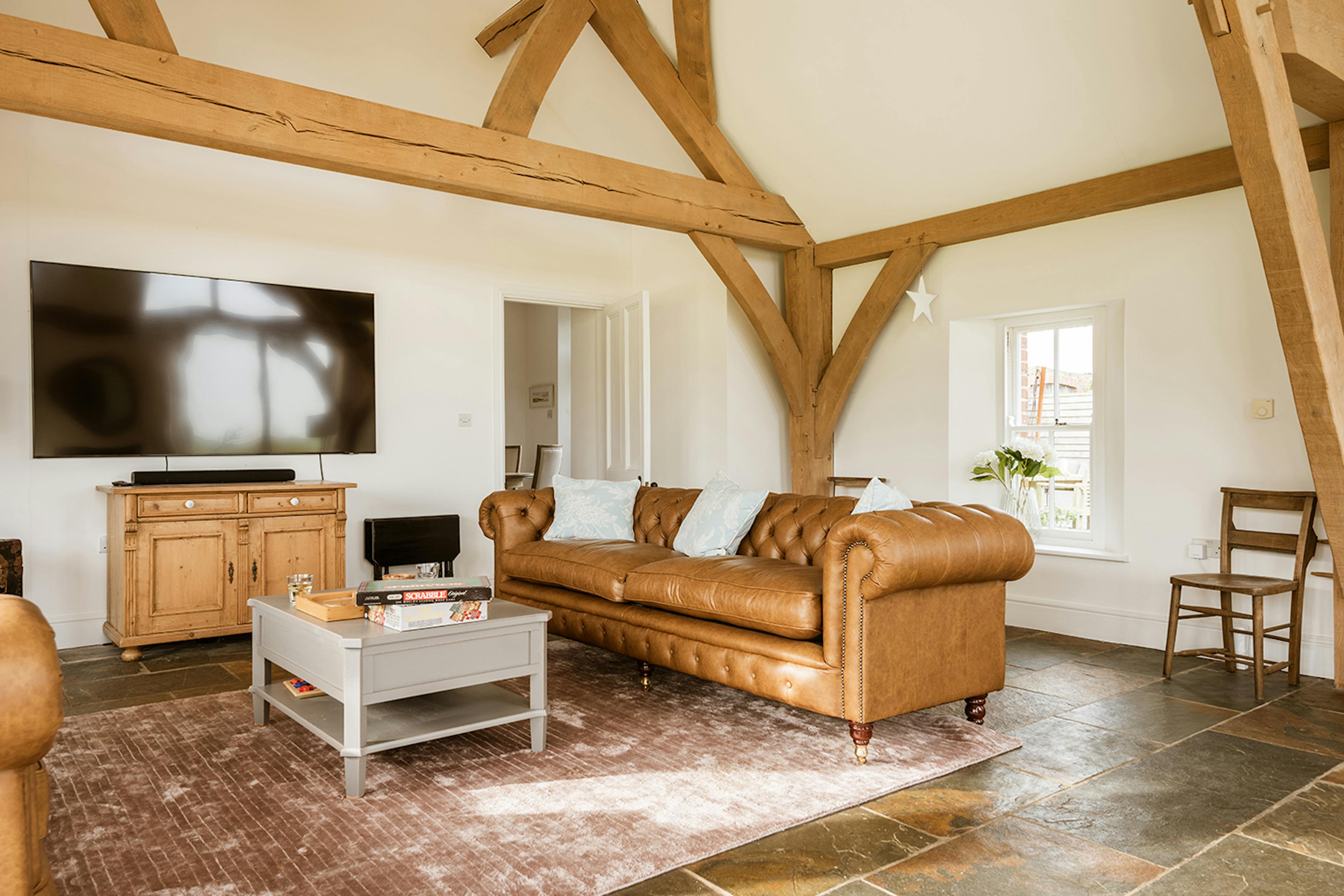 An oak framed extension with sitting area with leather sofas and a television