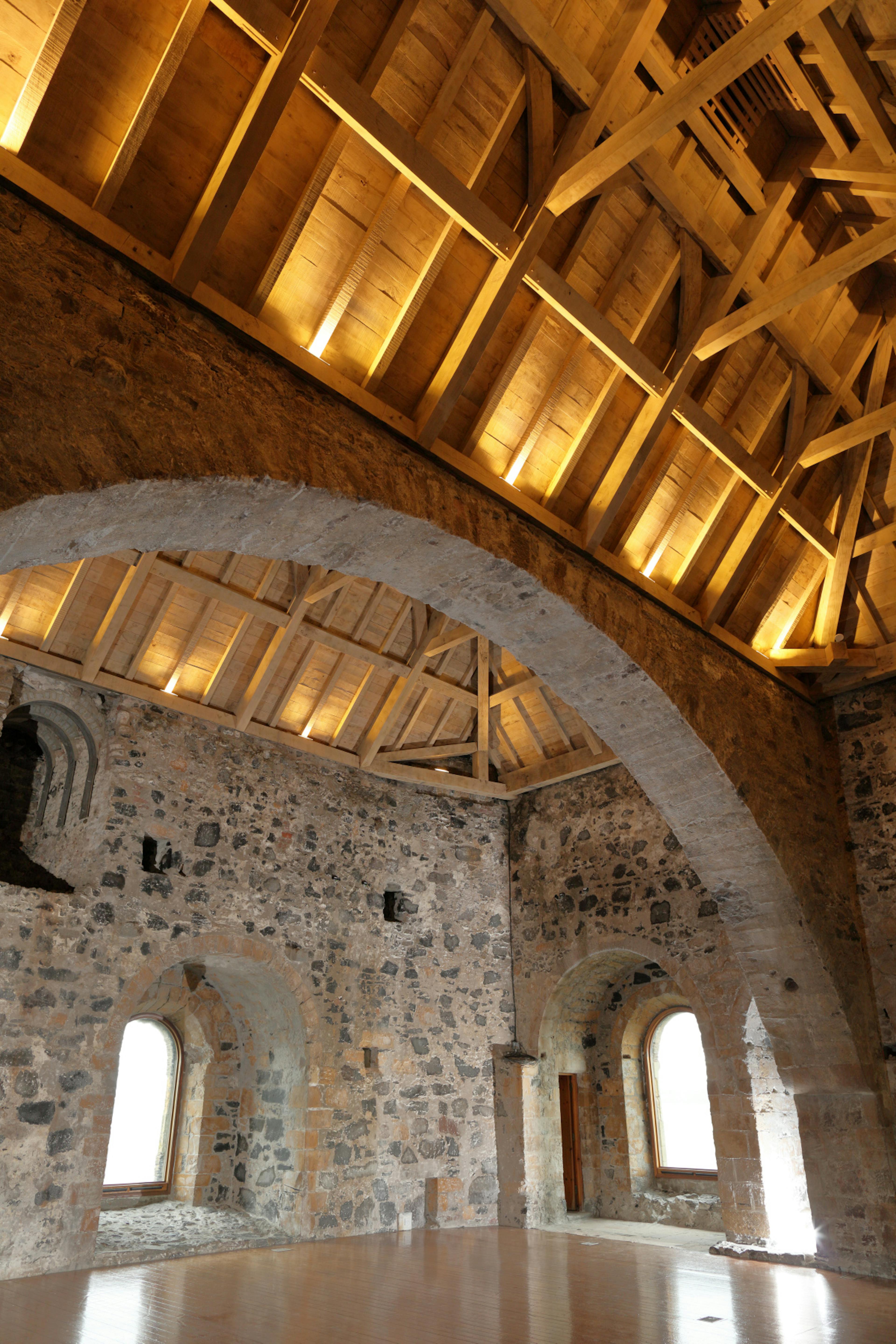 A green oak roof above a stone wall in the tower of a 12th century castle