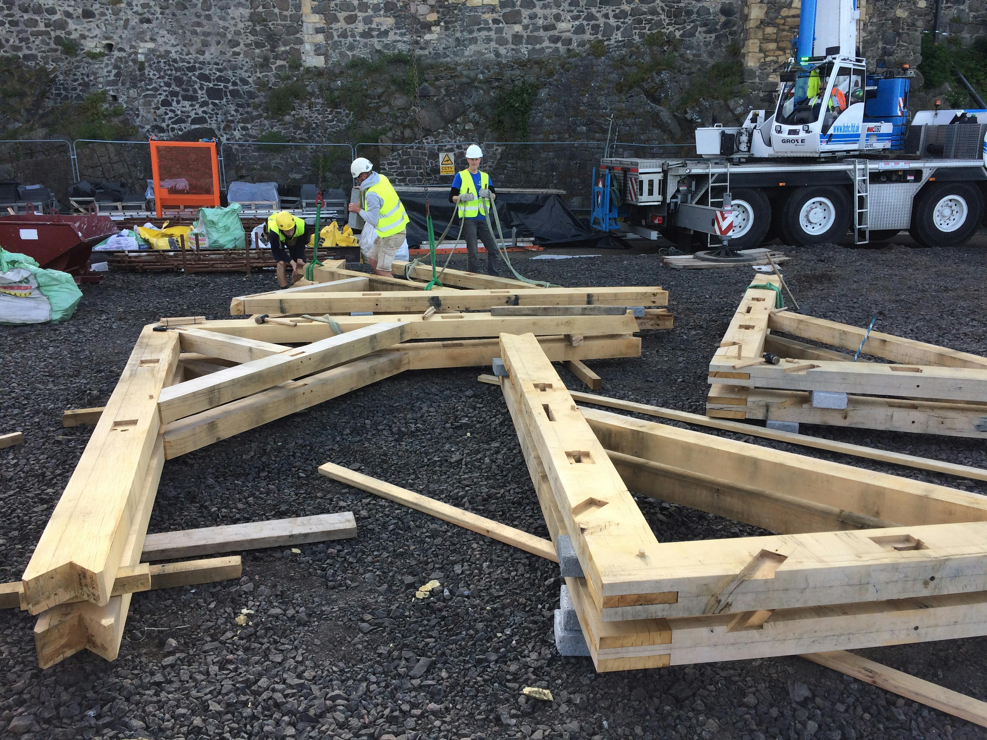 Four oak frame trusses are laid out at a construction site