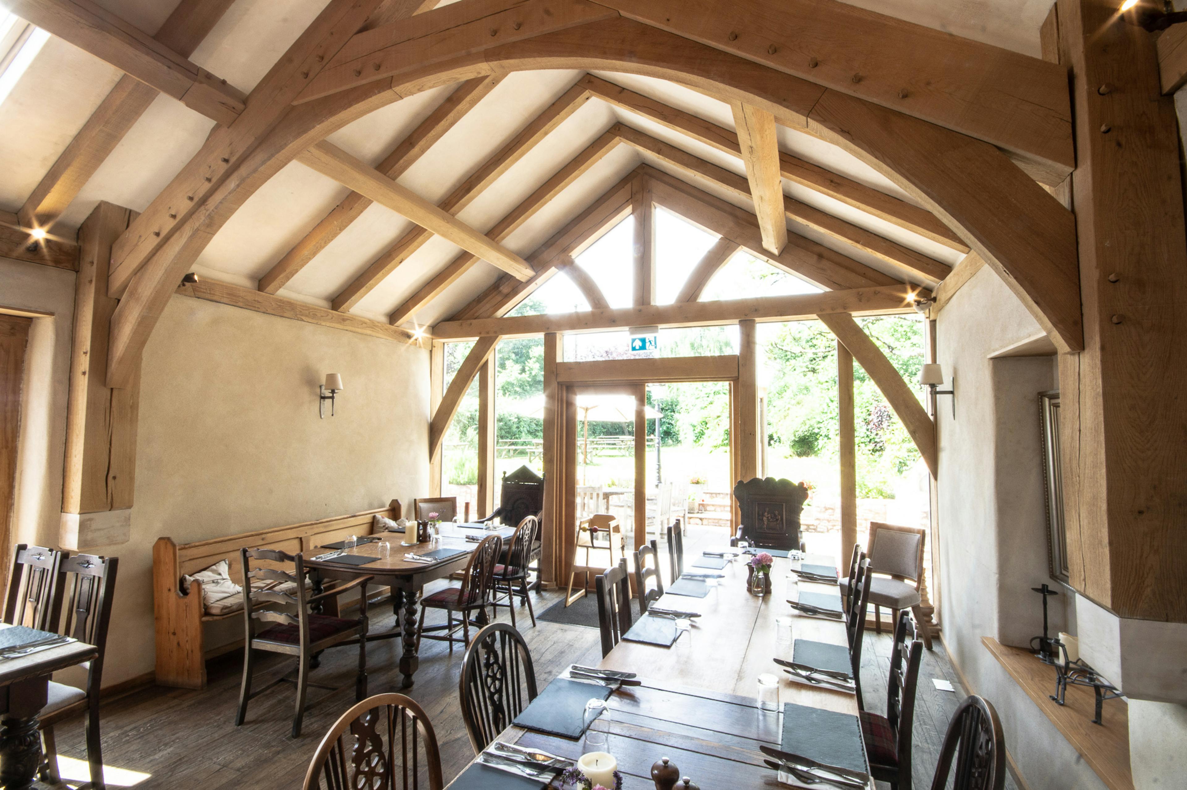 An oak framed dining room extension to a pub with a glazed gable end and doors out to a garden