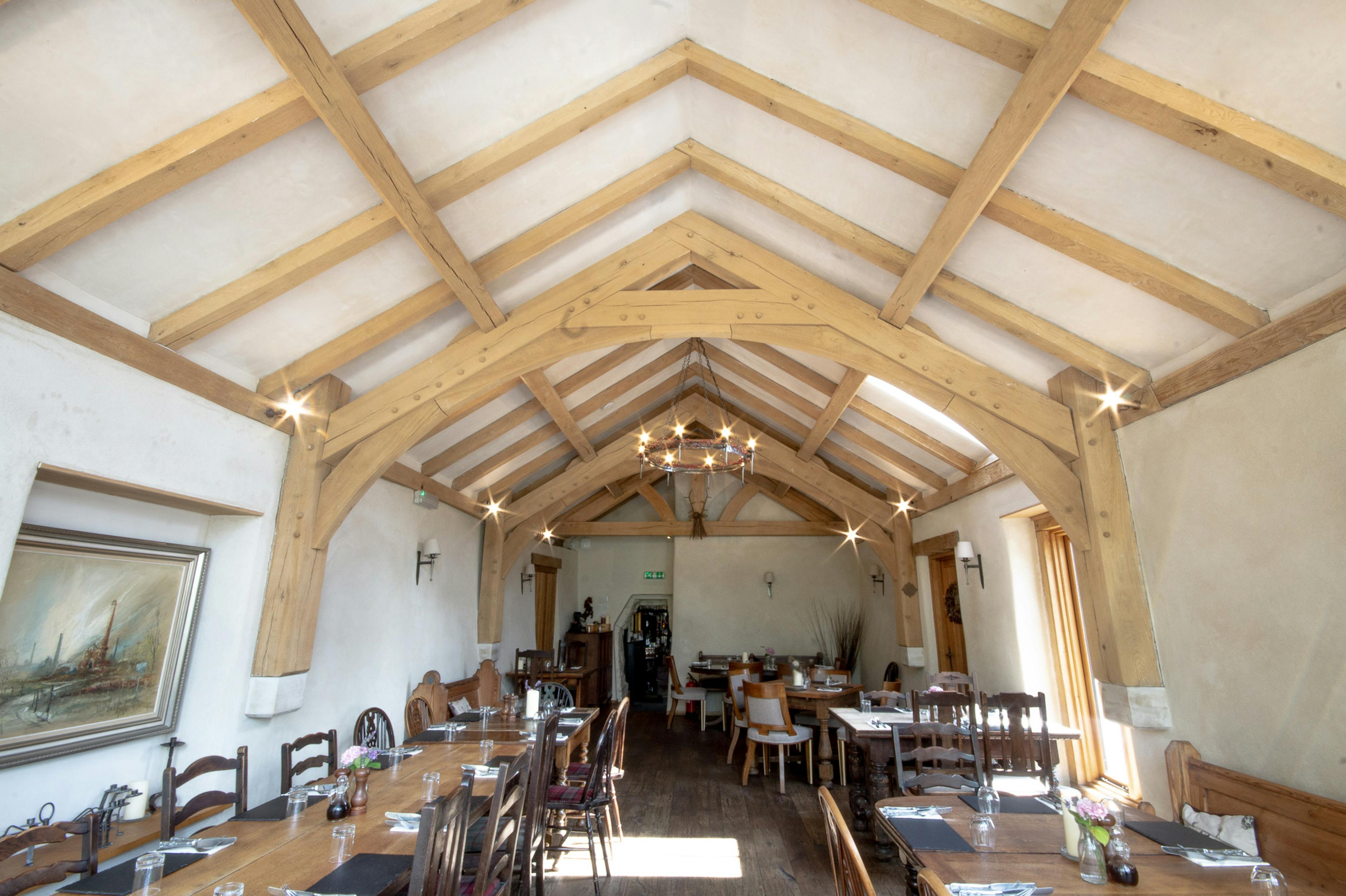 An oak framed dining room extension to a pub with a glazed gable end and doors out to a garden