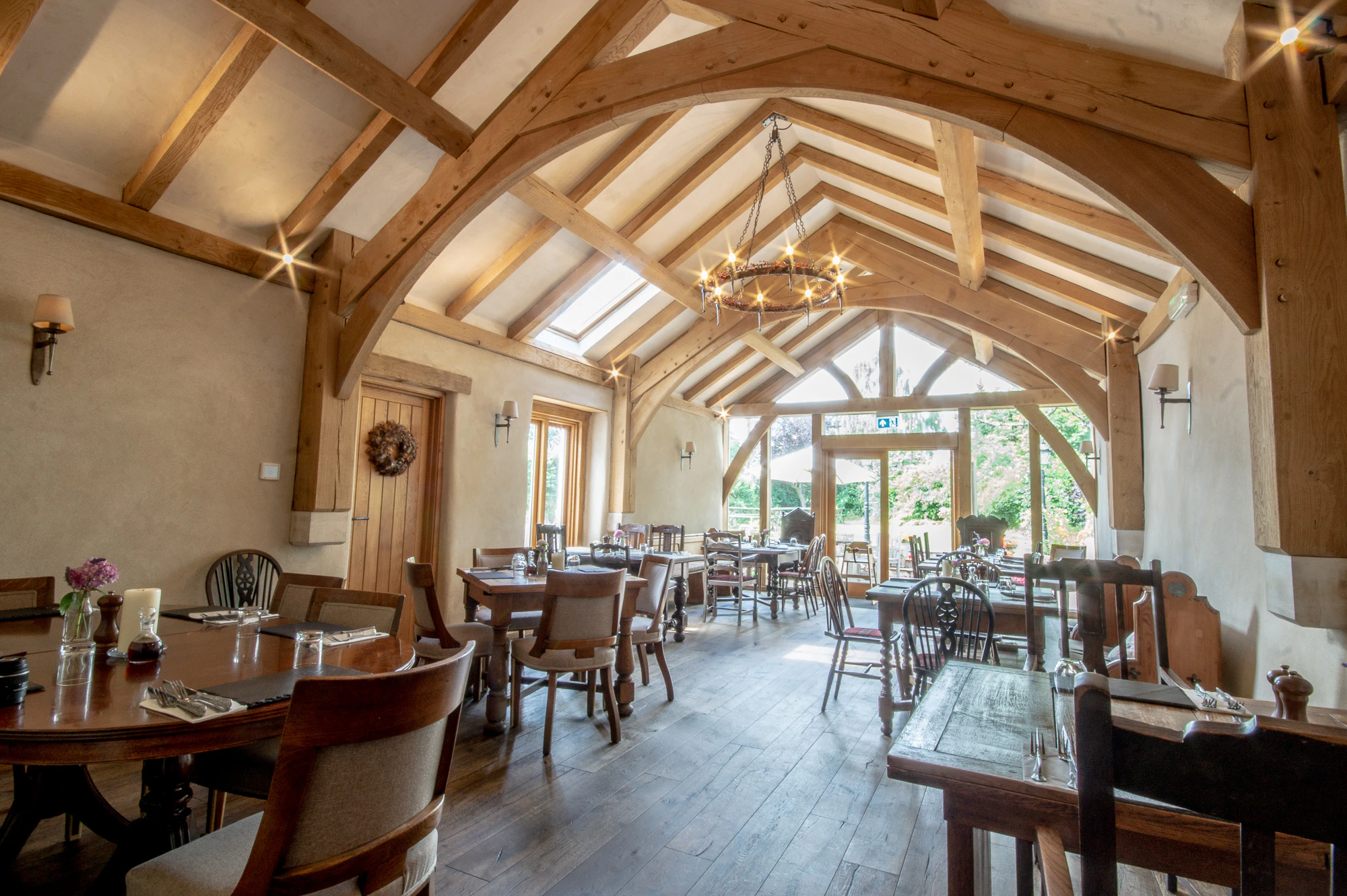 An oak framed dining room extension to a pub with a glazed gable end and doors out to a garden