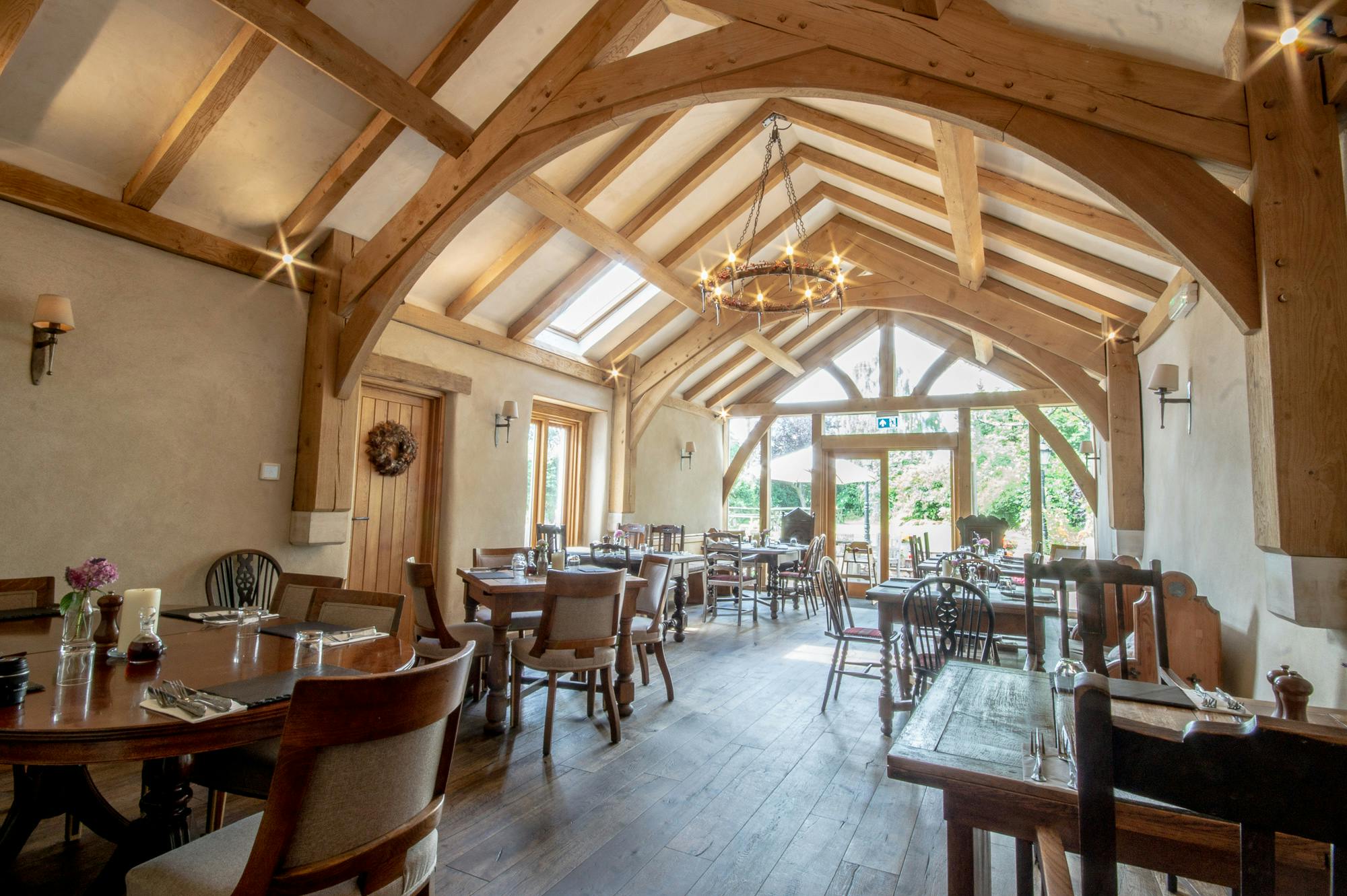 An oak framed dining room extension to a pub with a glazed gable end and doors out to a garden