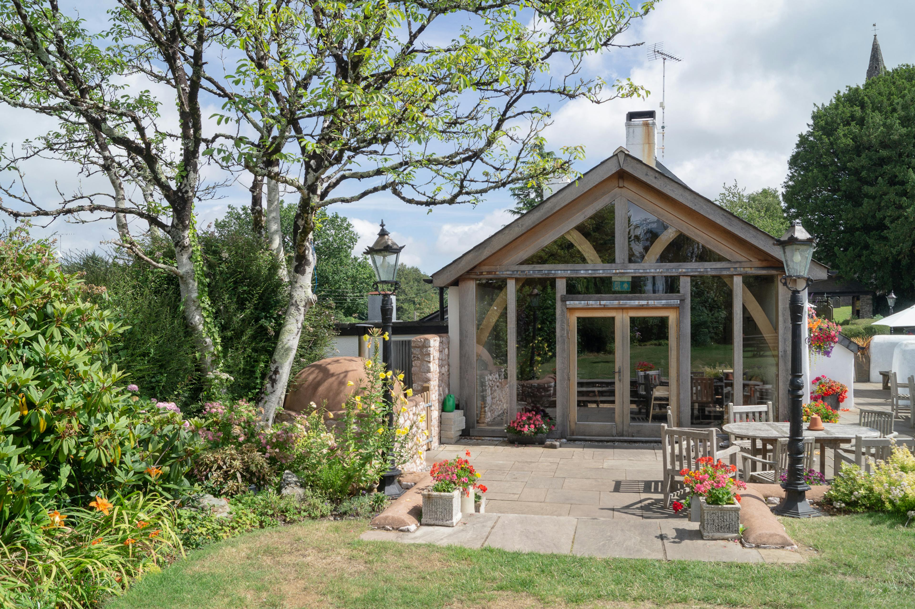 A pub garden with a green lawn and tables with an oak framed extension
