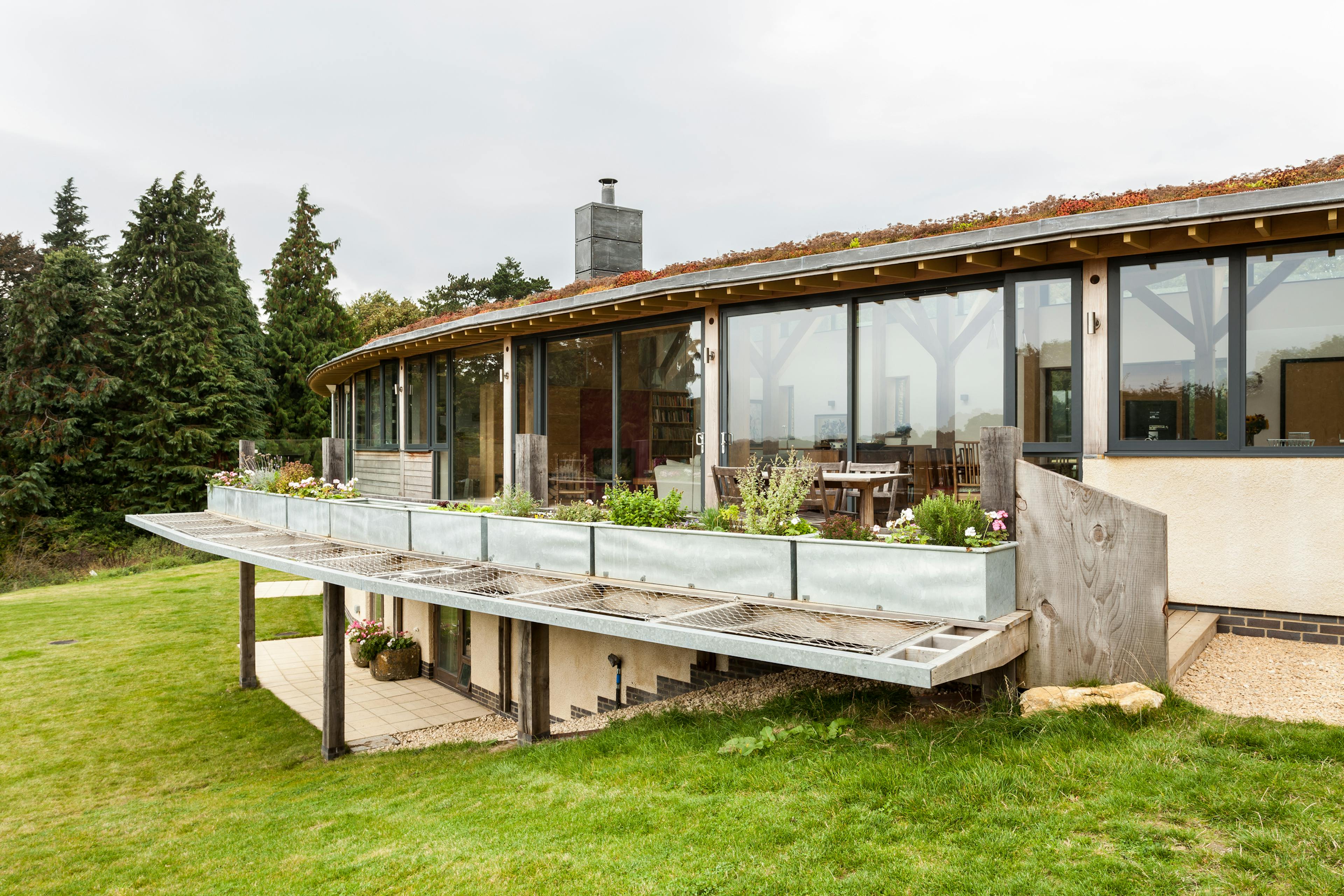 The back of a curved oak framed house with a green lawn