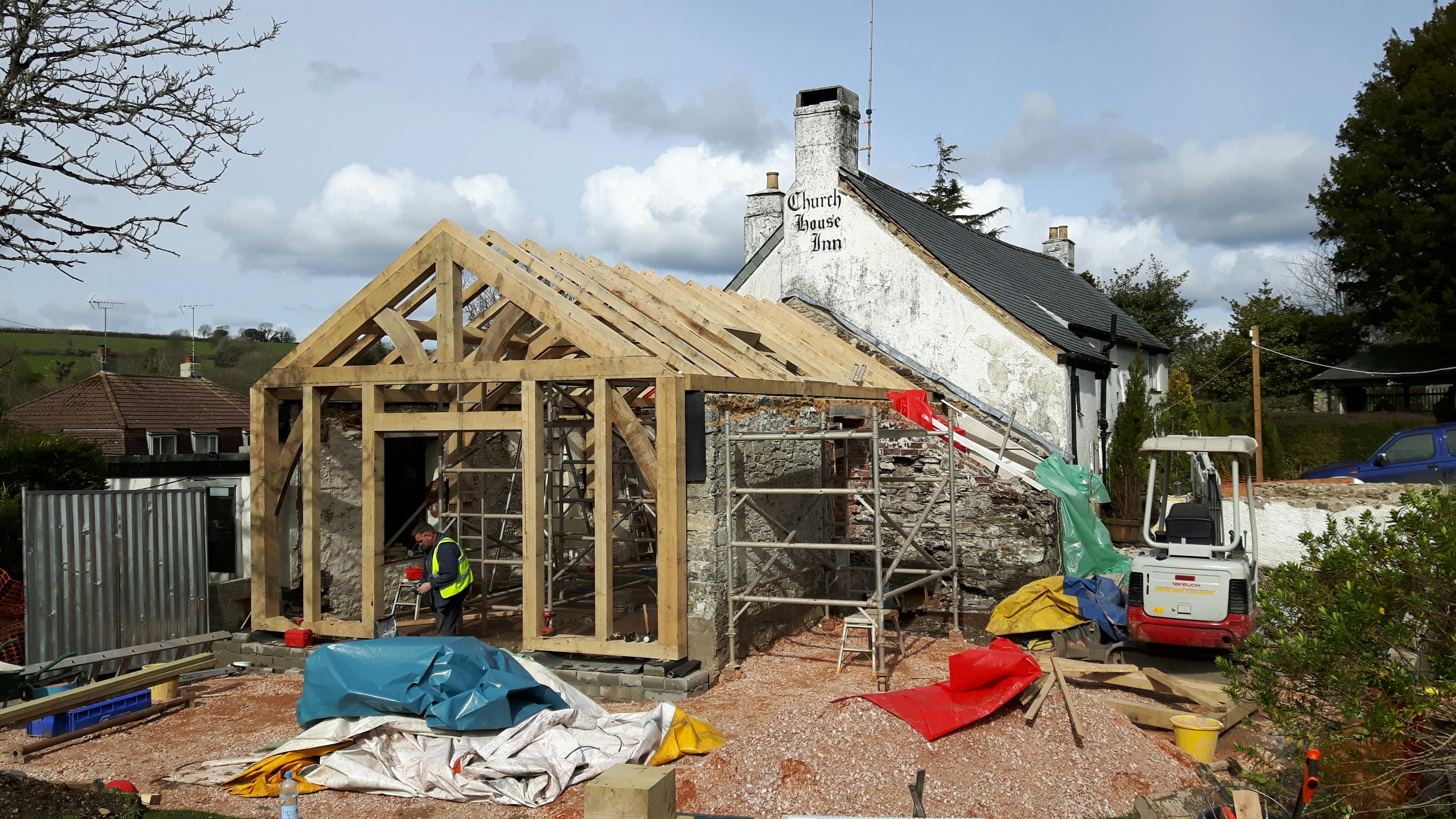 An oak framed extension to a pub being installed on a building site