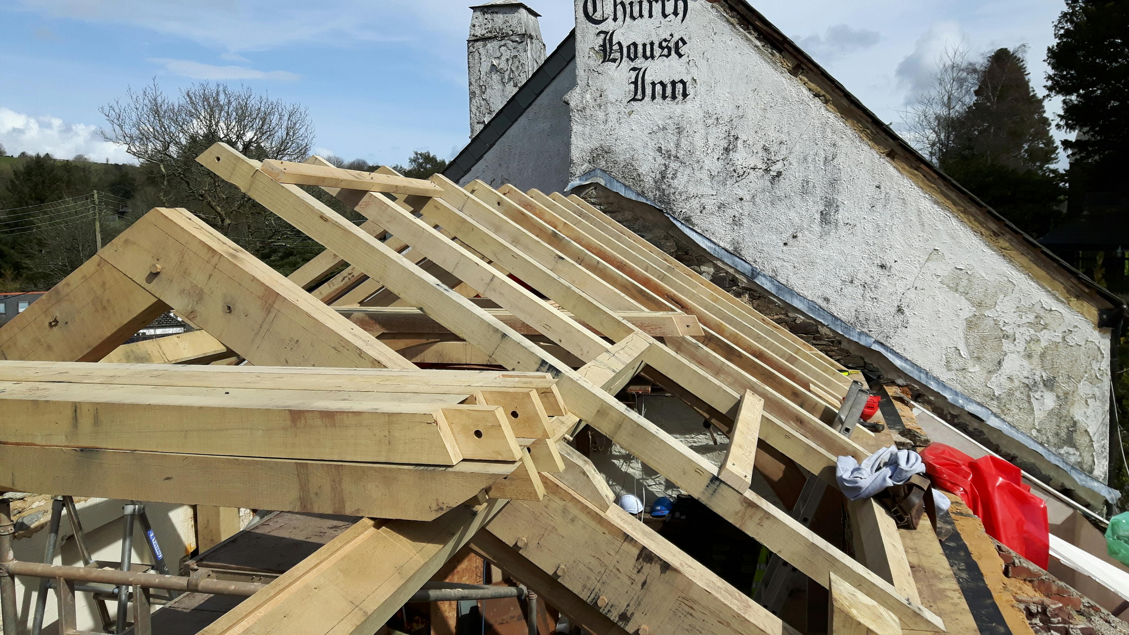 An oak framed extension to a pub being installed on a building site
