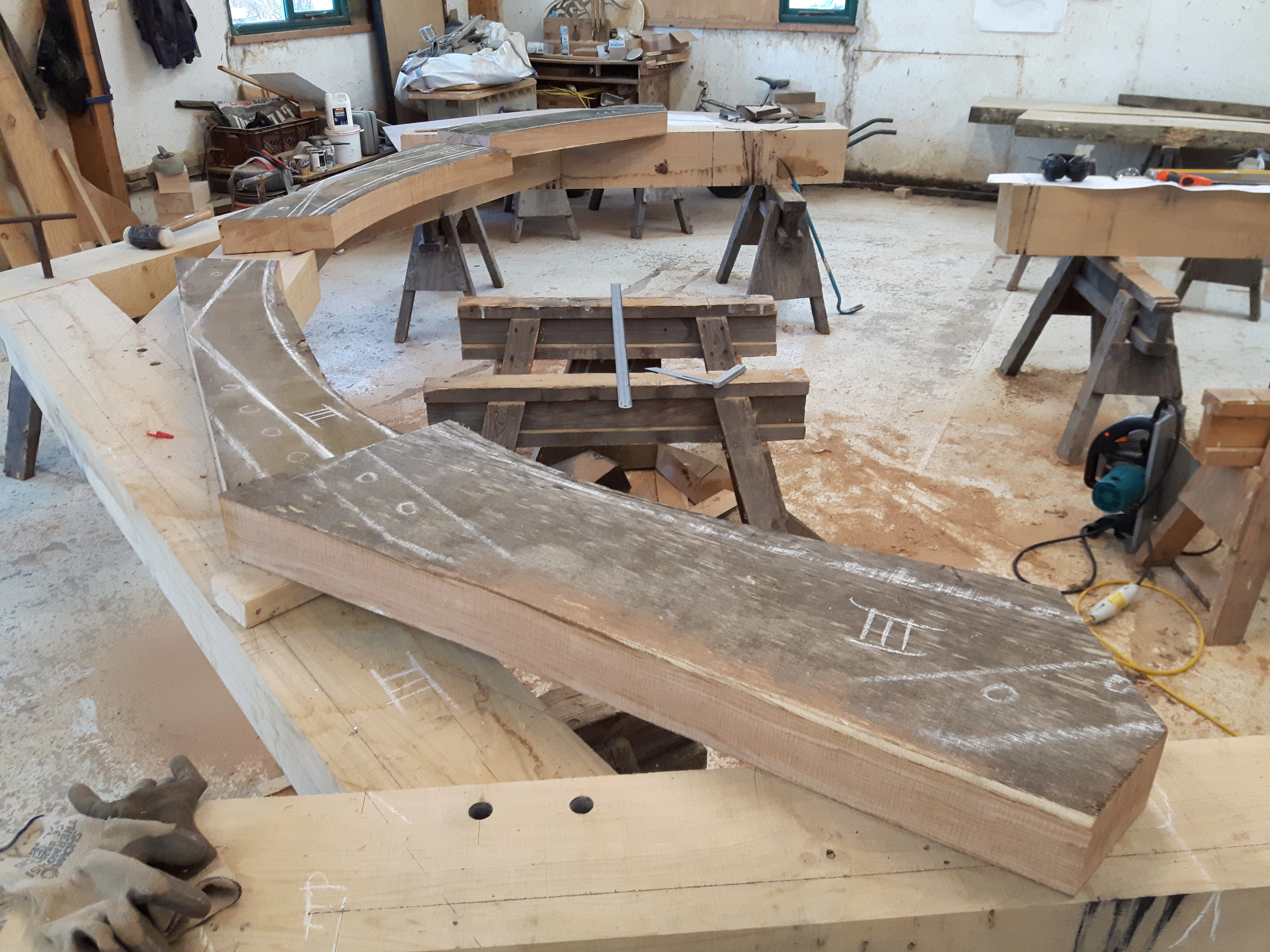An oak frame is laid out on trestle tables in a workshop