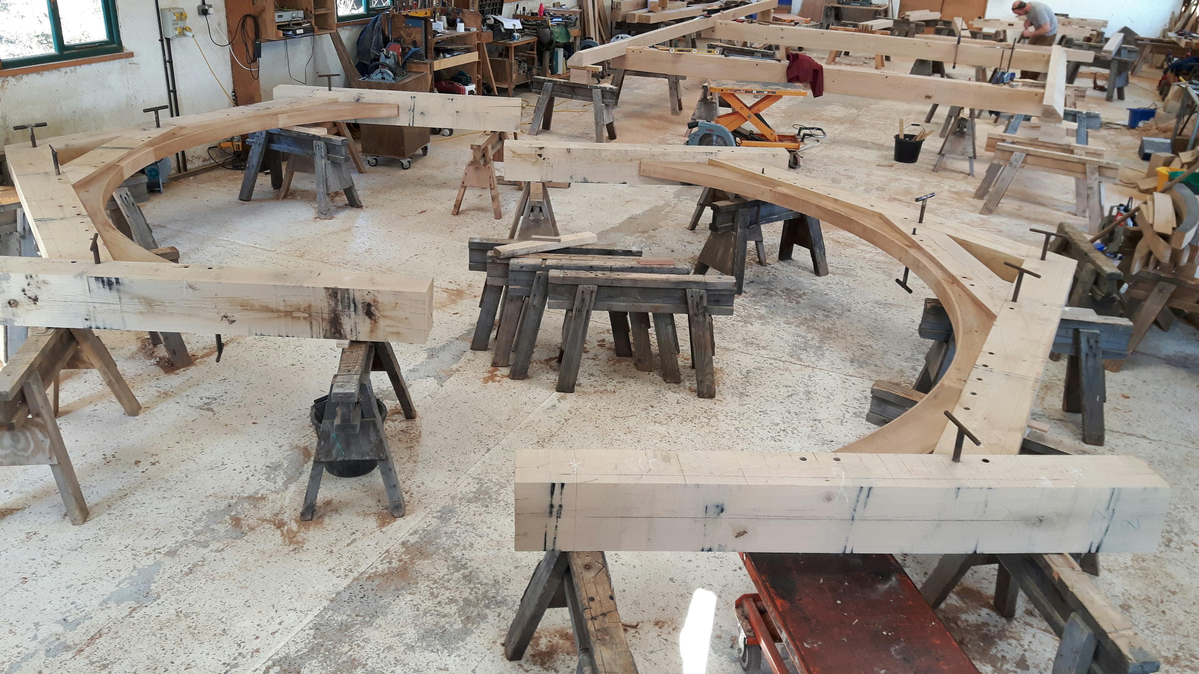An oak frame is laid out on trestle tables in a workshop