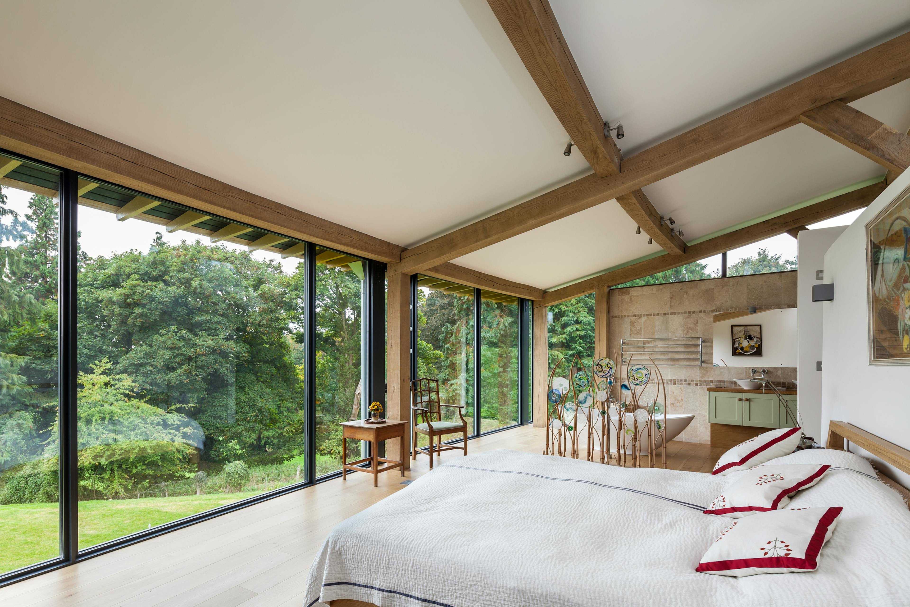 The bedroom of a curved oak framed house with large glazed windows