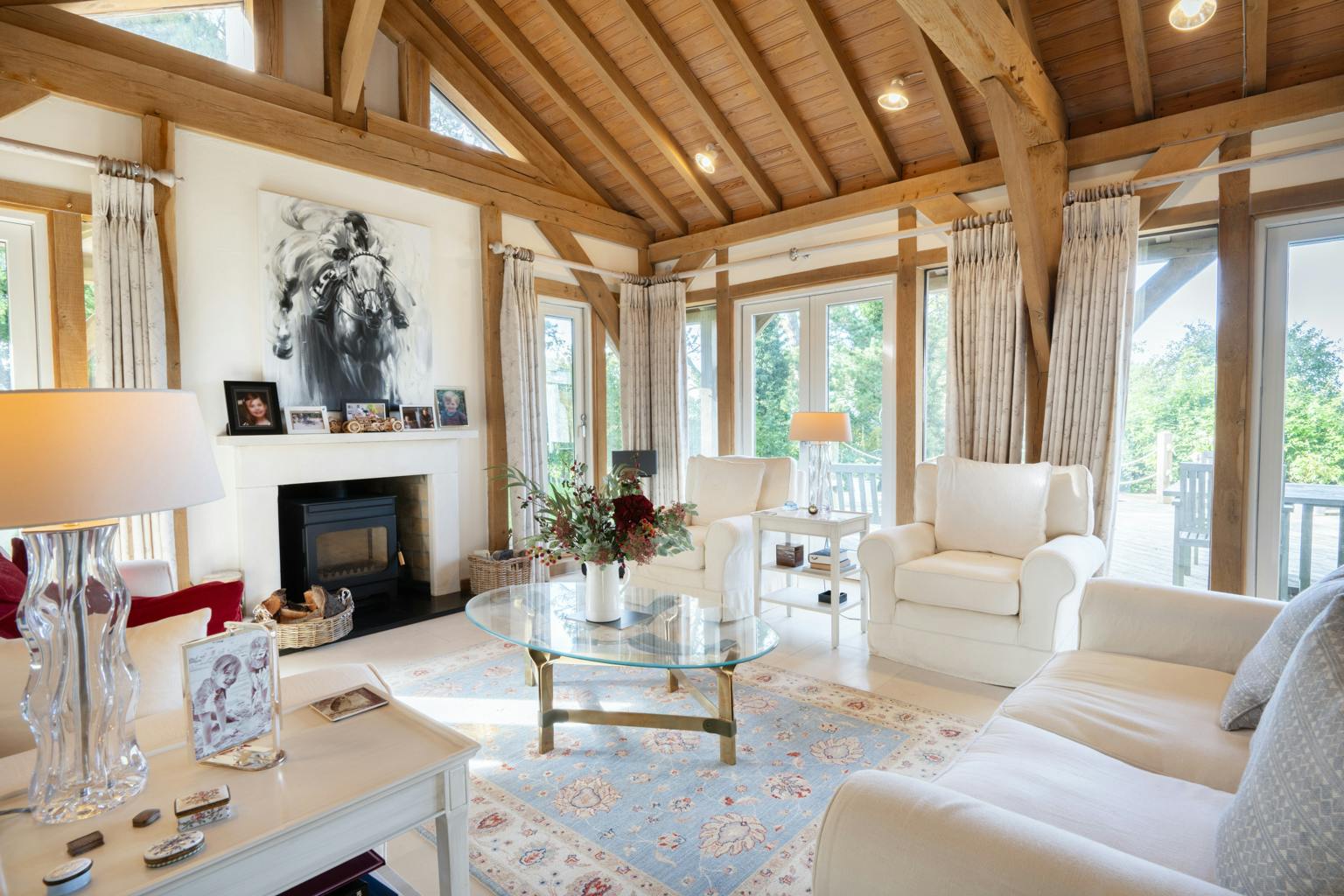 An oak framed sitting room showing sofas, armchairs, a log burner and large glazed windows