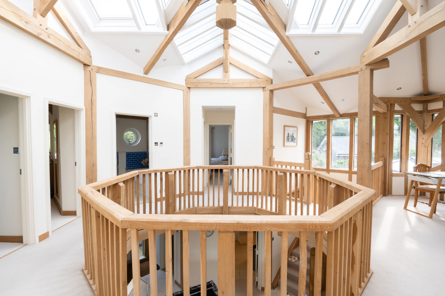 The upper floor landing of an oak frame home showing an octagonal bannister with rooms coming off it