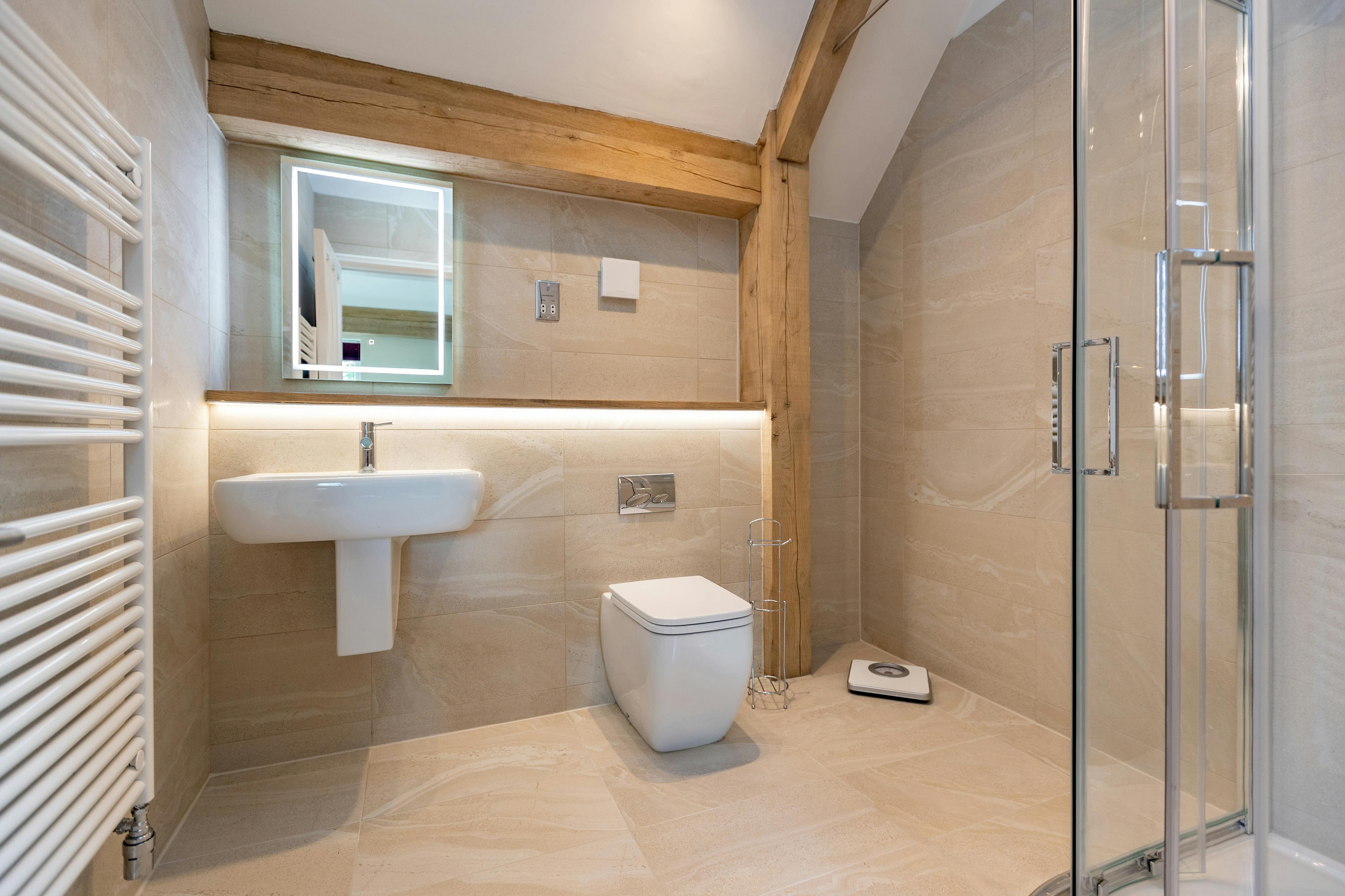 An oak framed bathroom showing a toilet, sink and shower