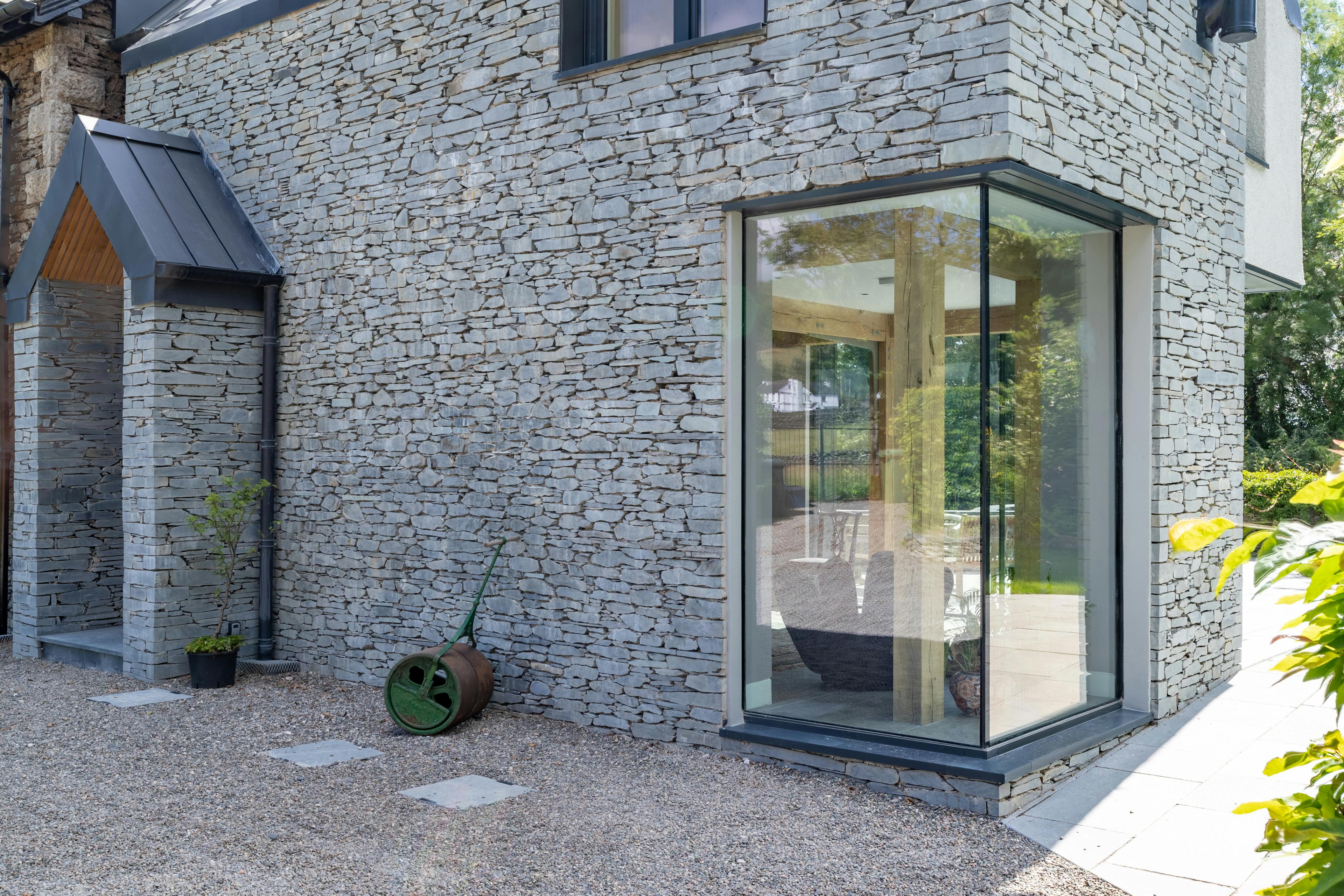 An oak frame living room extension to an Edwardian vicarage with a stonework finish